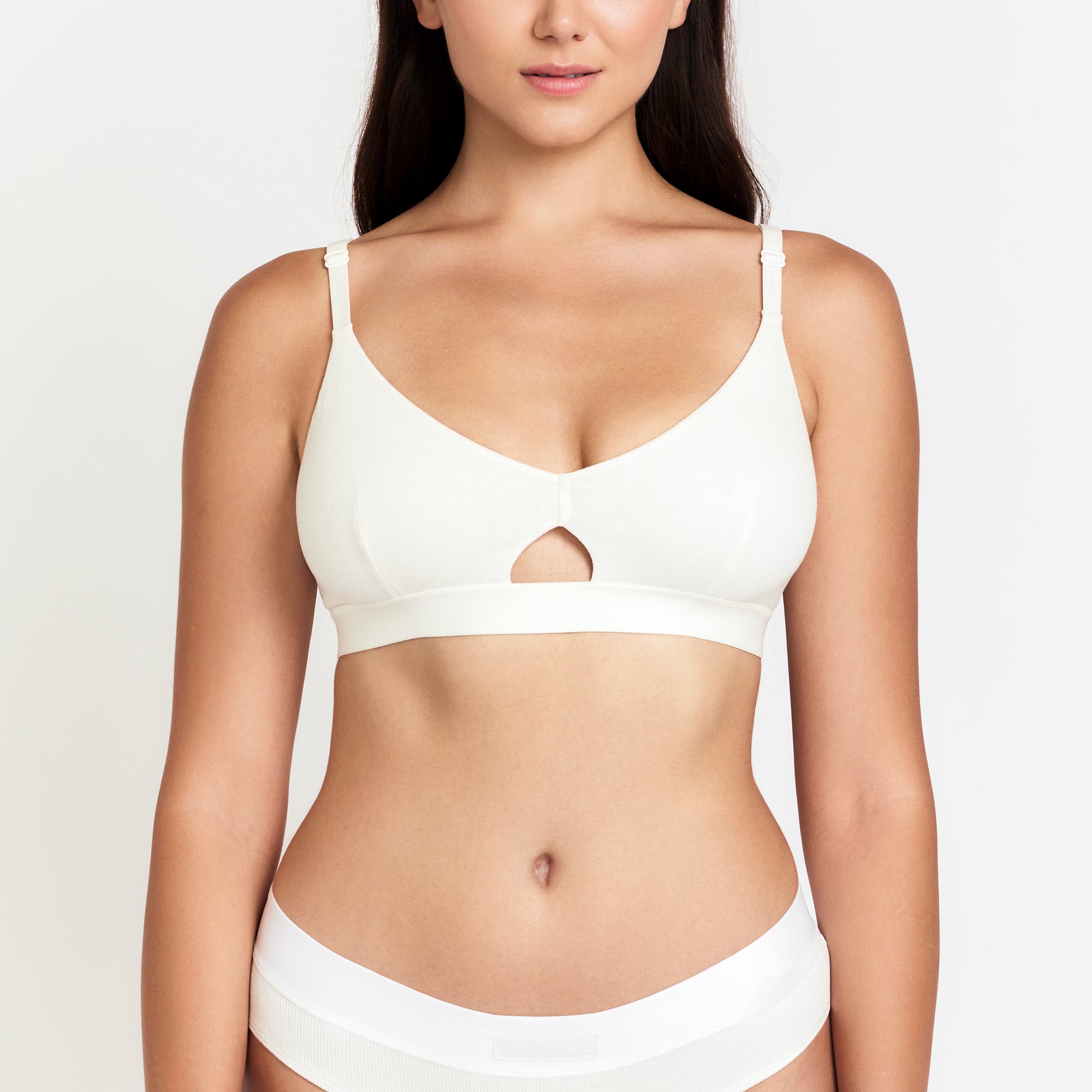 Woman wearing a white bra and underwear set on a plain background