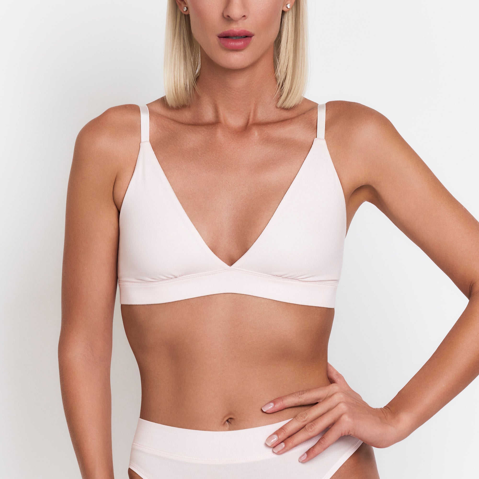 Woman wearing a white bra and underwear set on a plain background