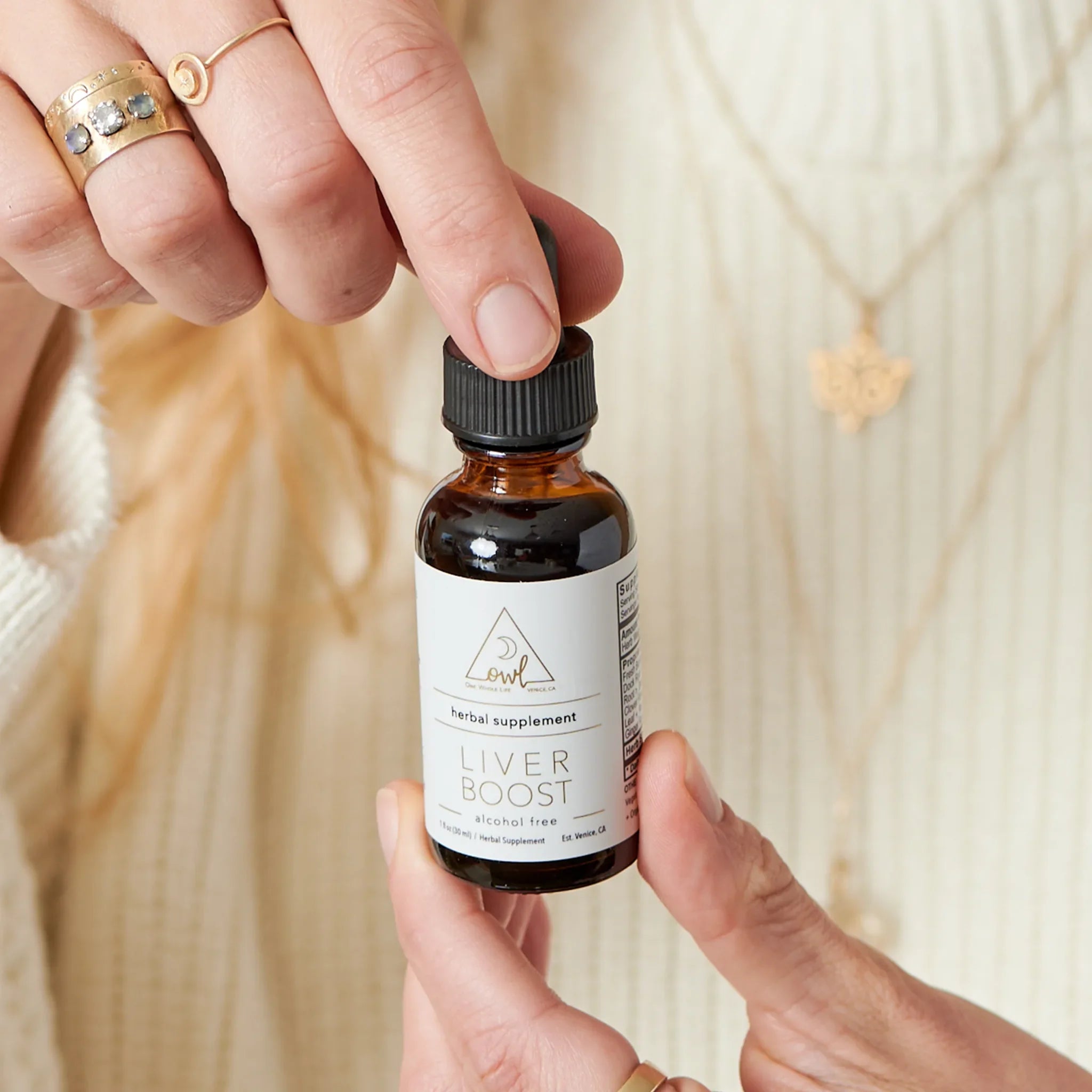 Bottle labeled 'Liver Boost' held by a person against a neutral background
