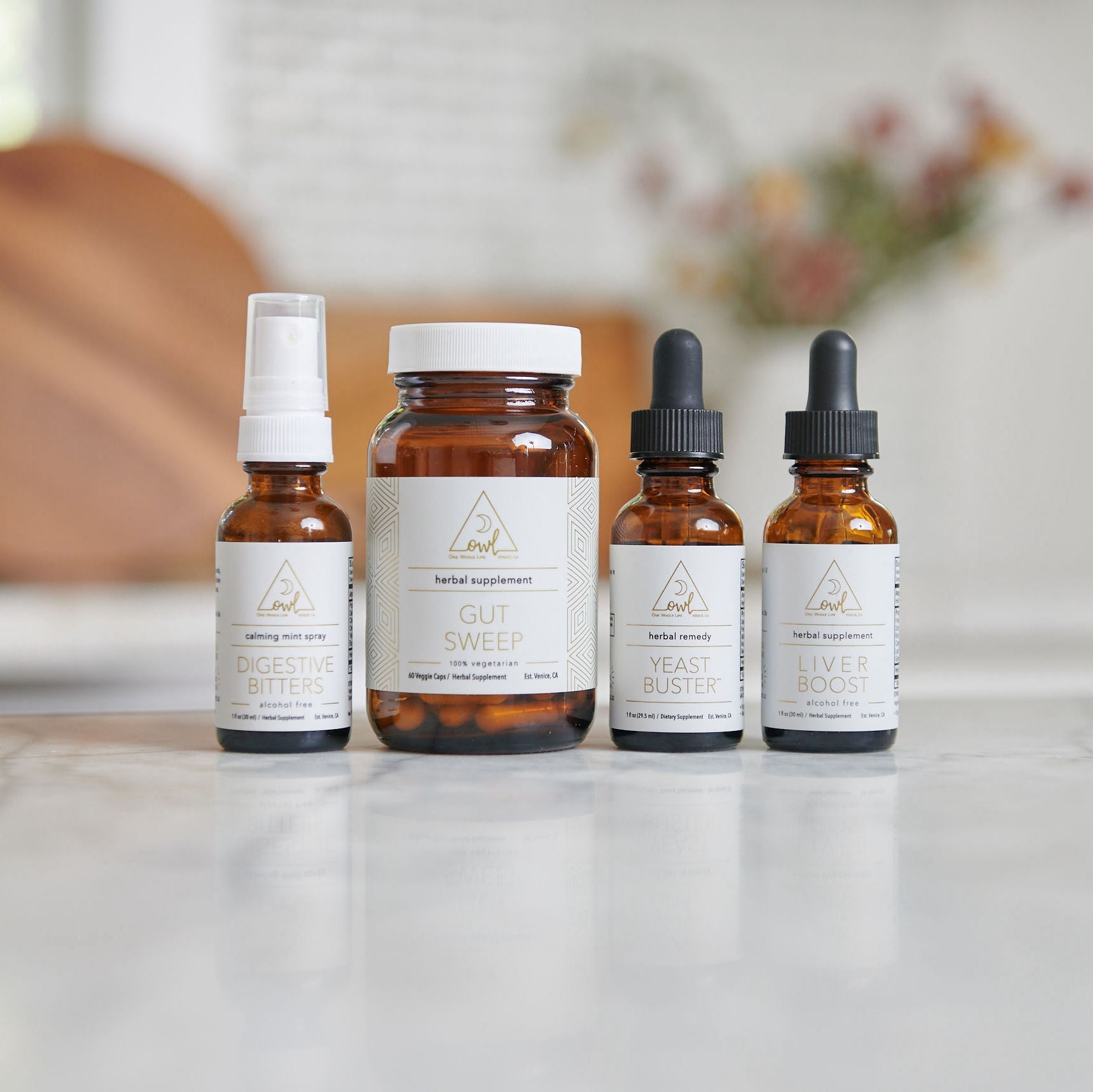 Four bottles of herbal supplements on a marble surface with a blurred background