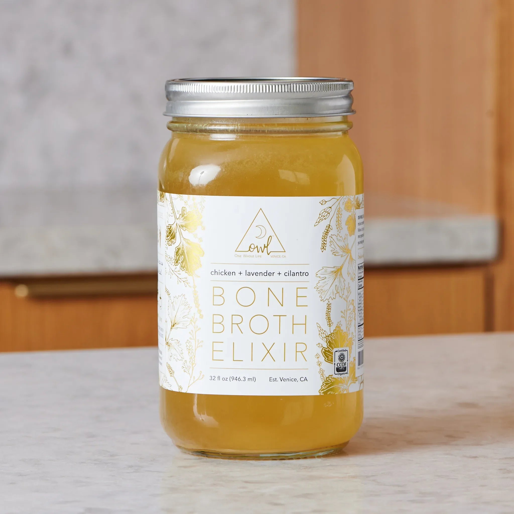Jar of bone broth elixir with a label on a neutral background