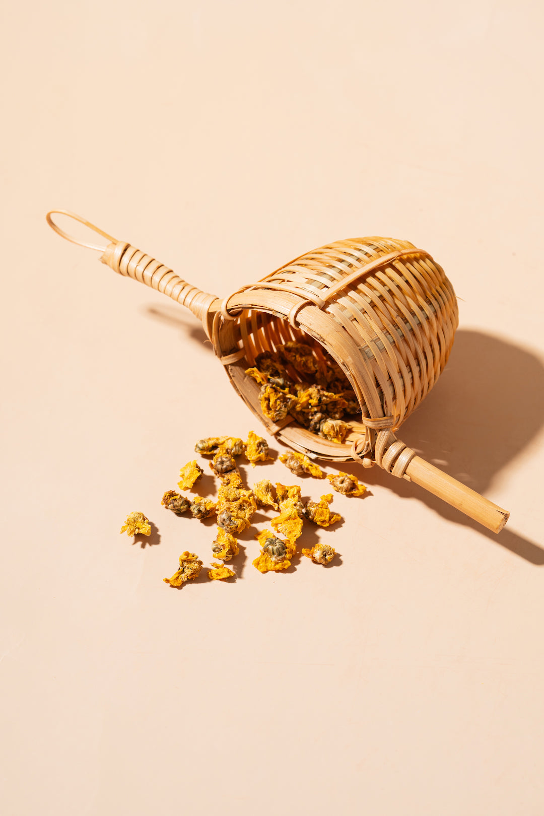 Wicker basket with dried yellow flowers on a beige background