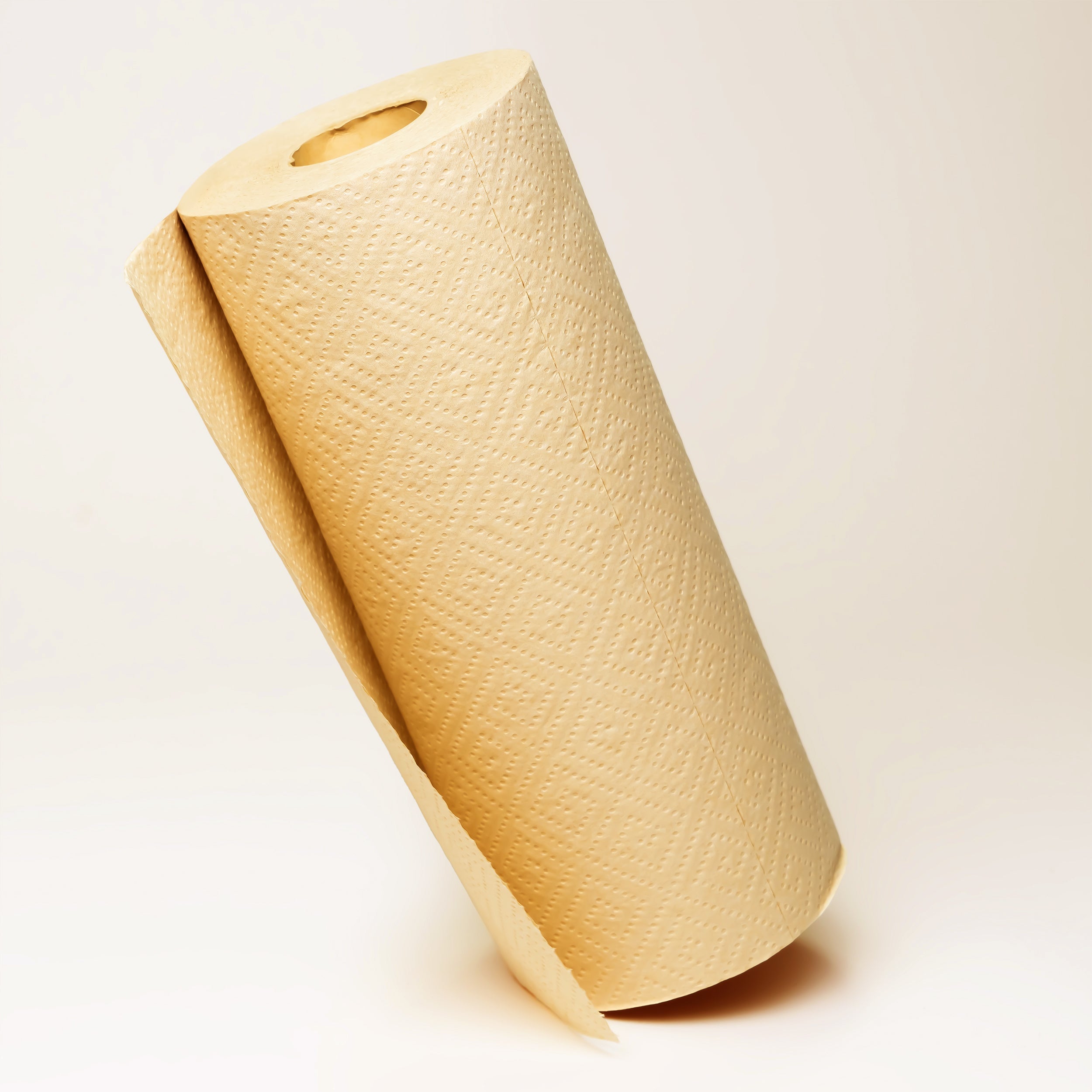 Roll of beige paper towel on a light beige background