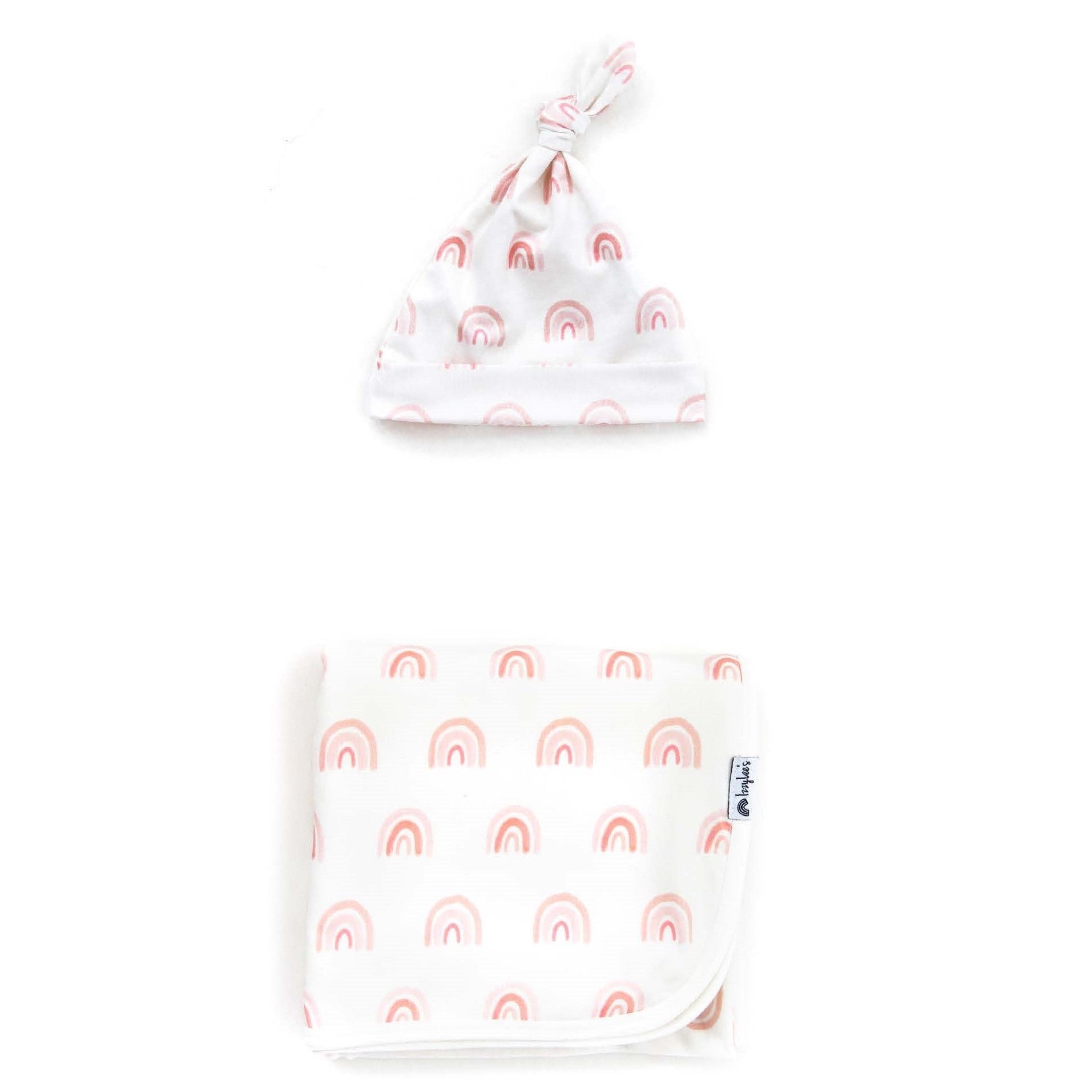 Baby hat and blanket set with pink rainbow patterns on a white background