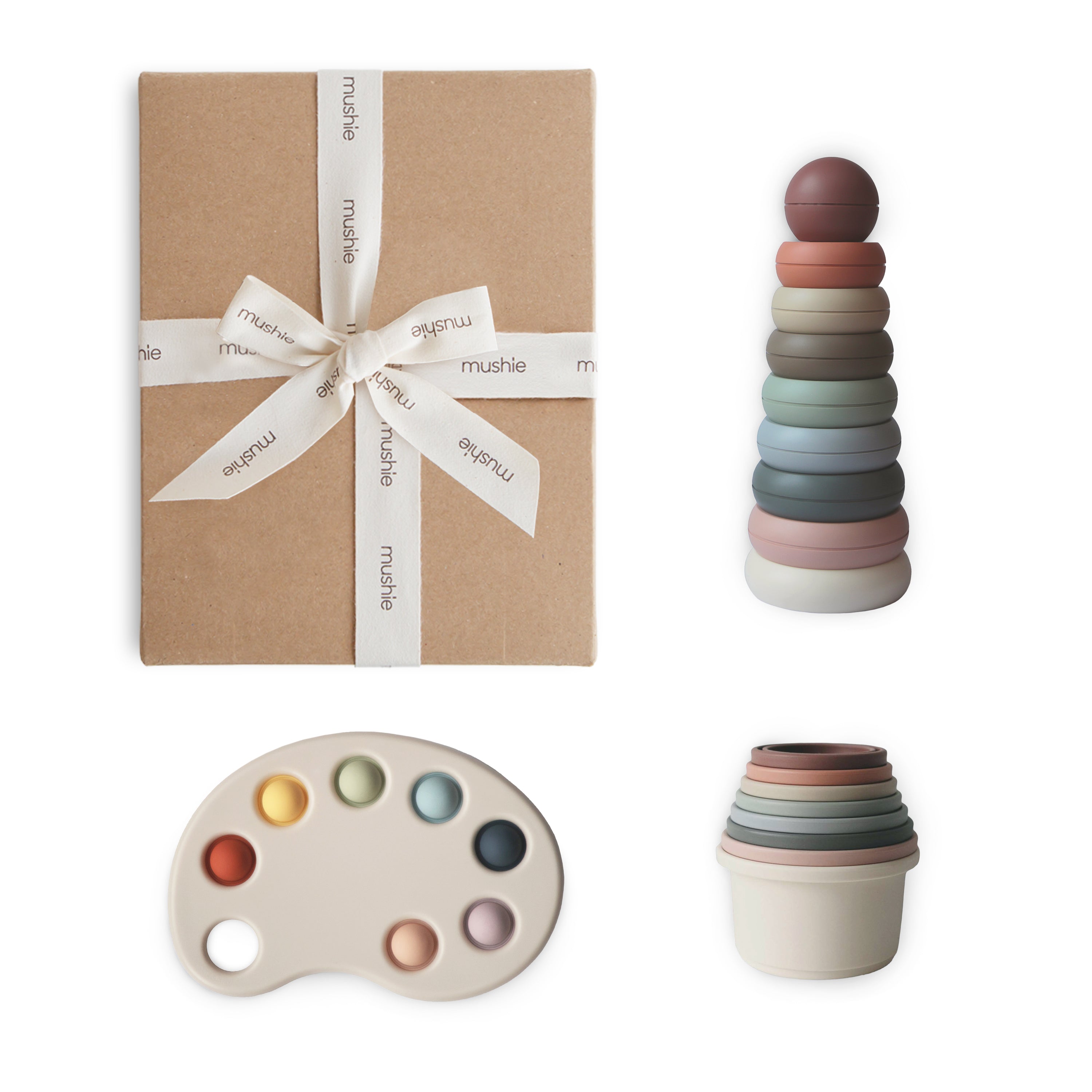 Gift box with ribbon, colorful stacking cups, and paint palette on a white background