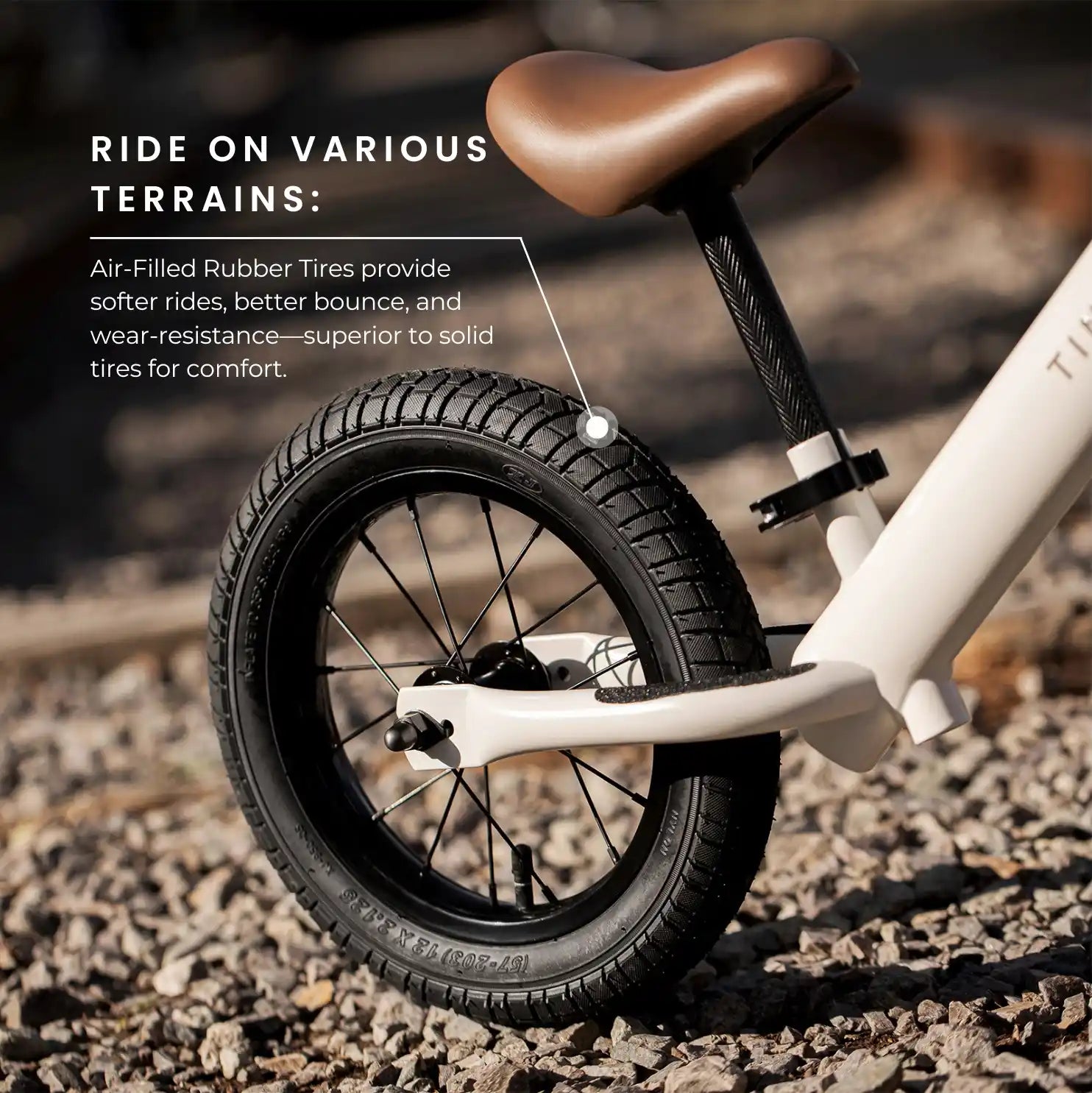 Children's balance bike with air-filled rubber tire on a rocky surface