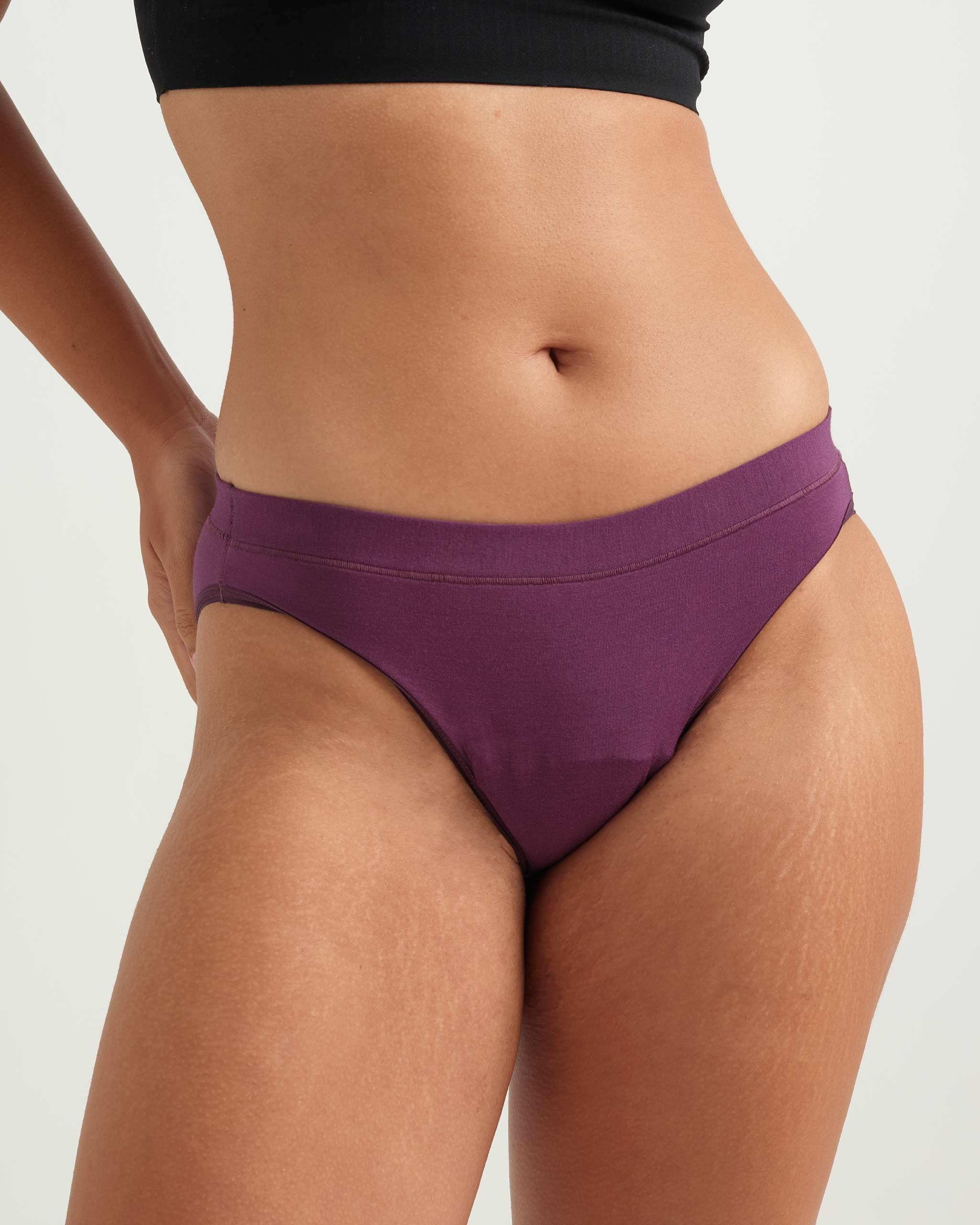 Purple bikini bottom worn by a person on a plain background