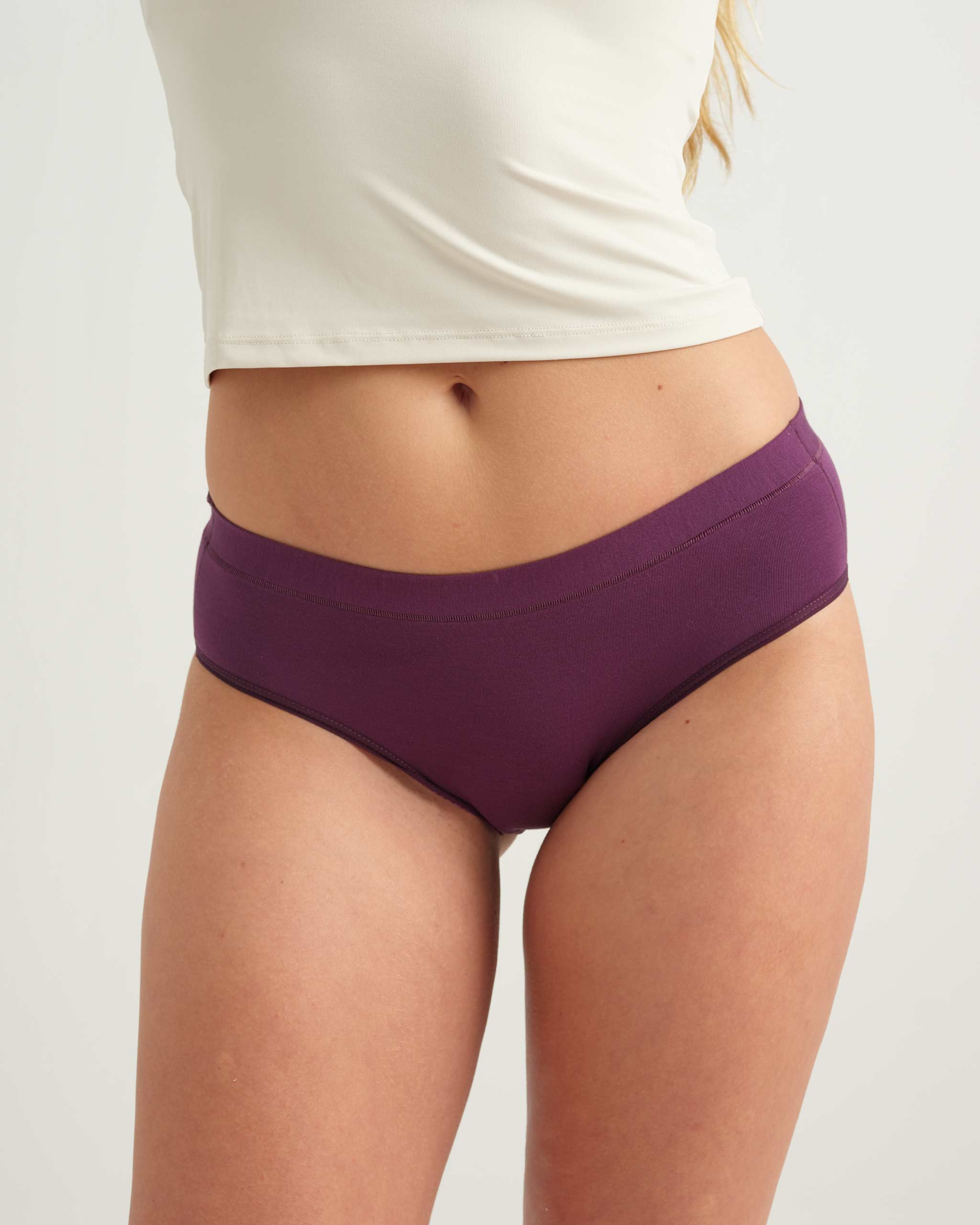 Purple underwear worn by a person on a plain background