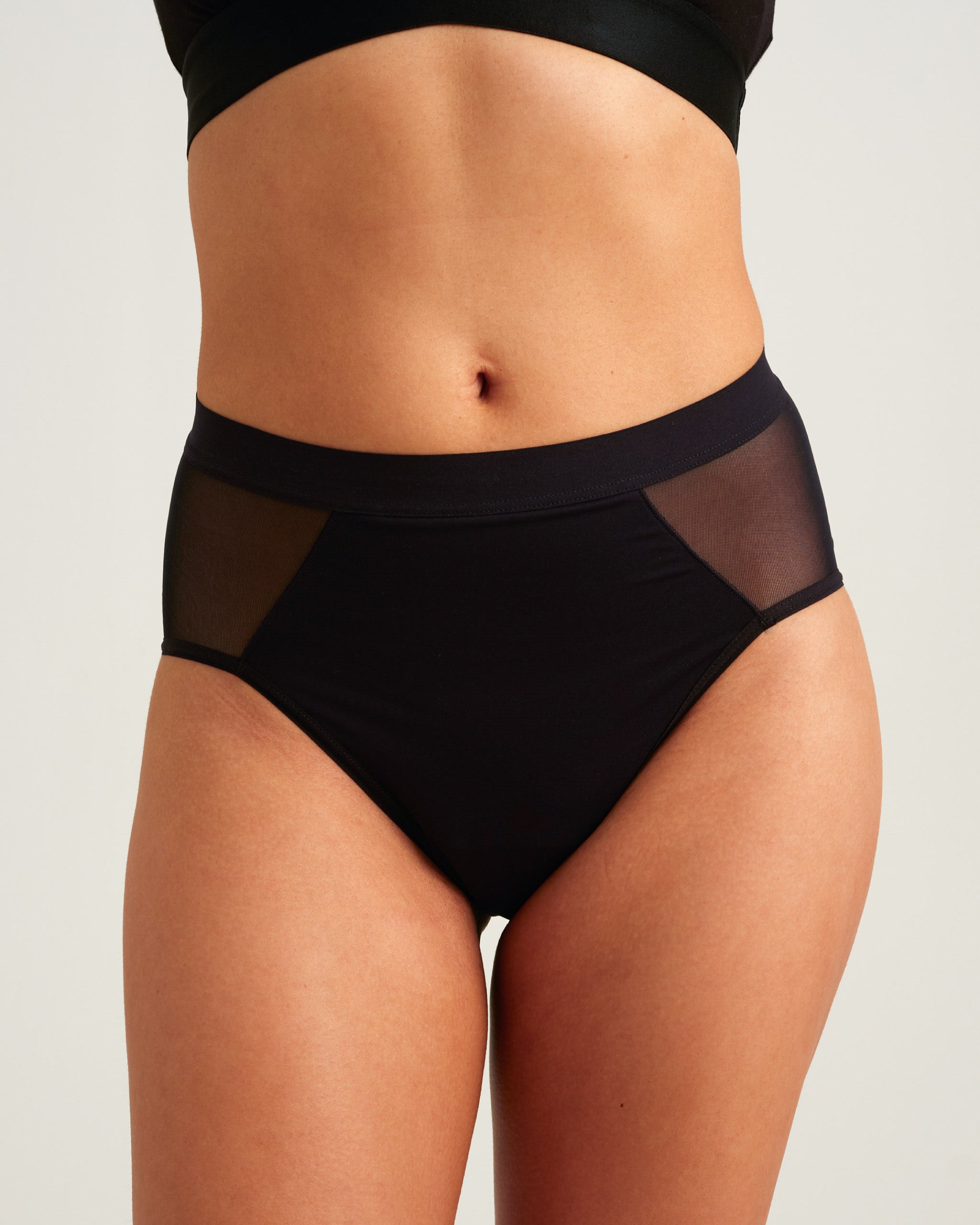 Black high-waisted underwear with mesh panels on a neutral background