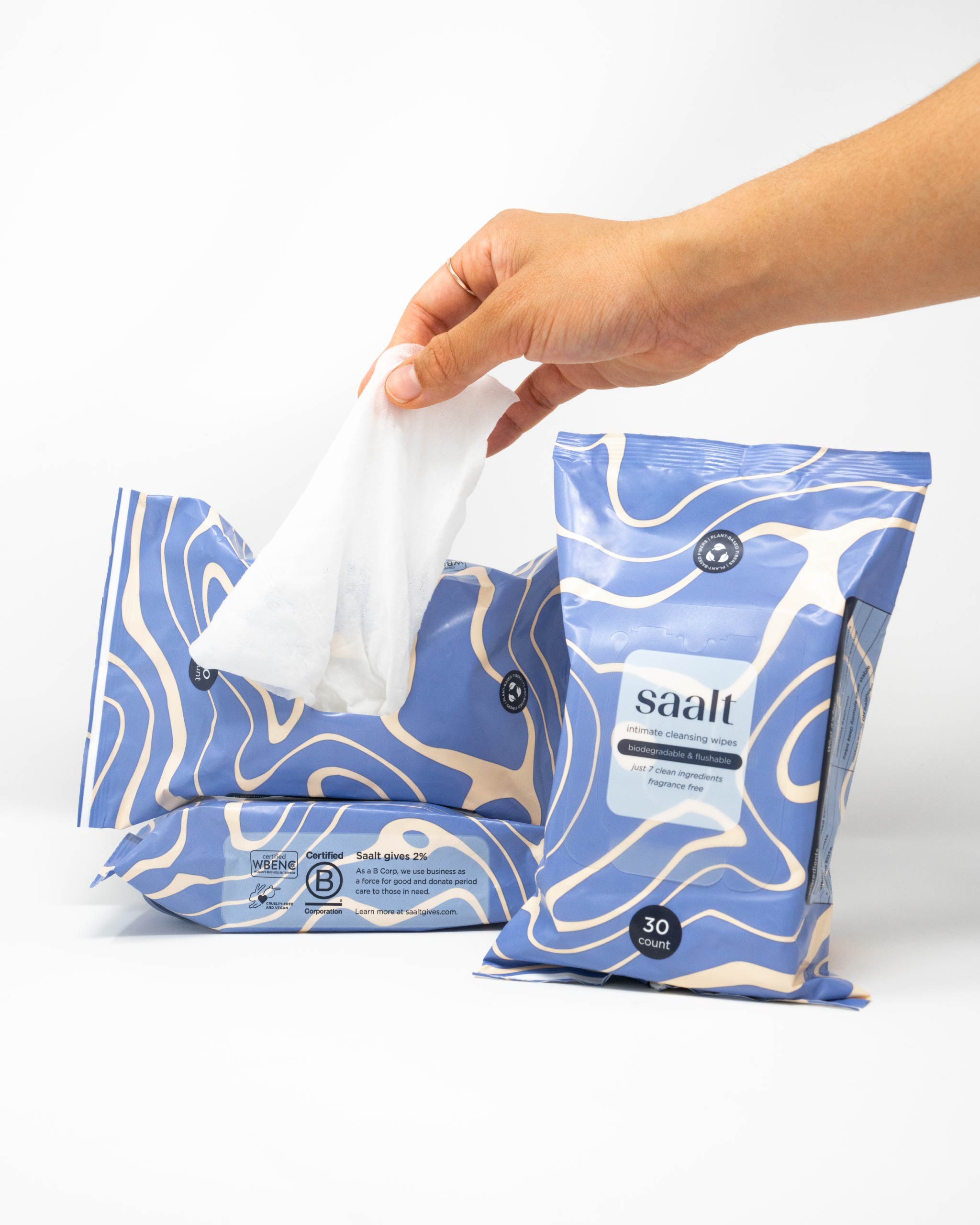 Hand reaching for a tissue from a blue and white patterned tissue pack labeled 'saalt' on a white background.