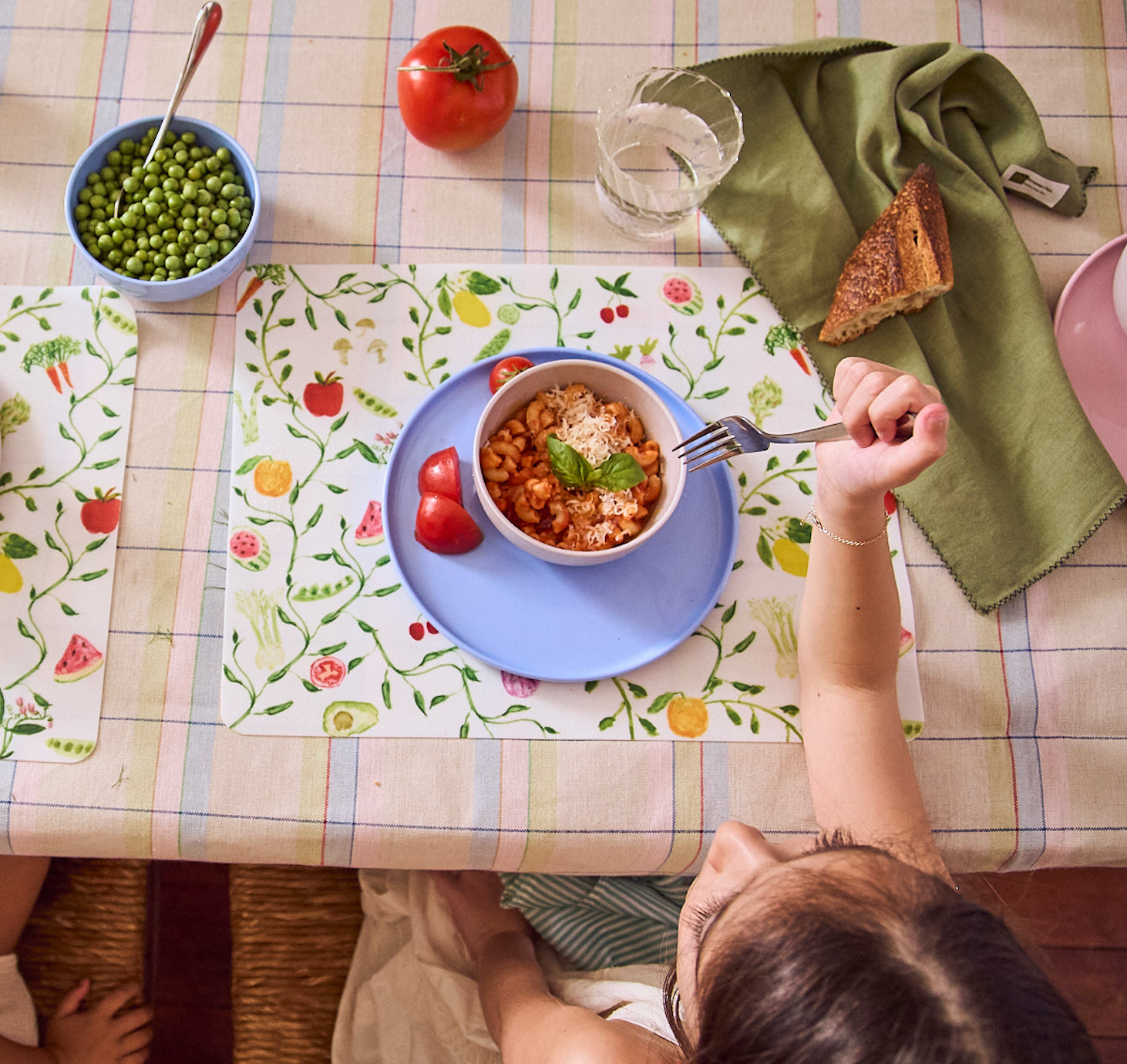 Child eating a bowl of pasta at a table with a colorful placemat