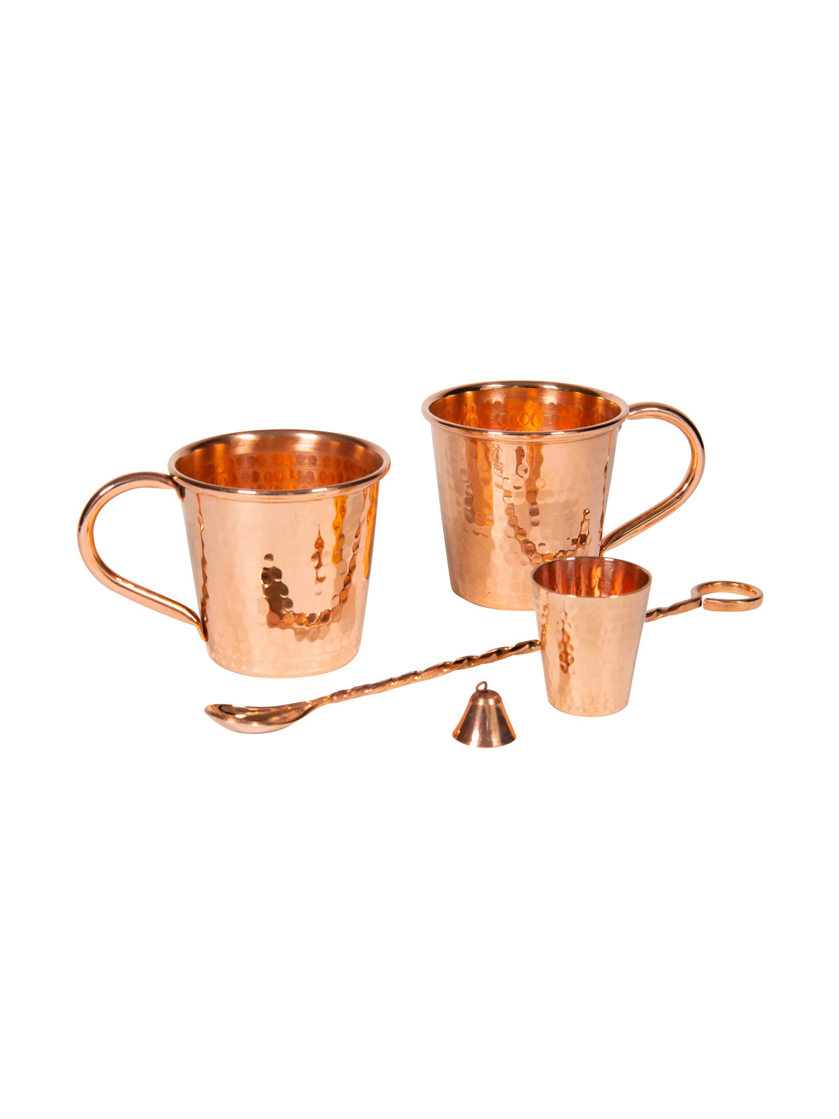 Set of three copper mugs with a spoon and small container on a white background