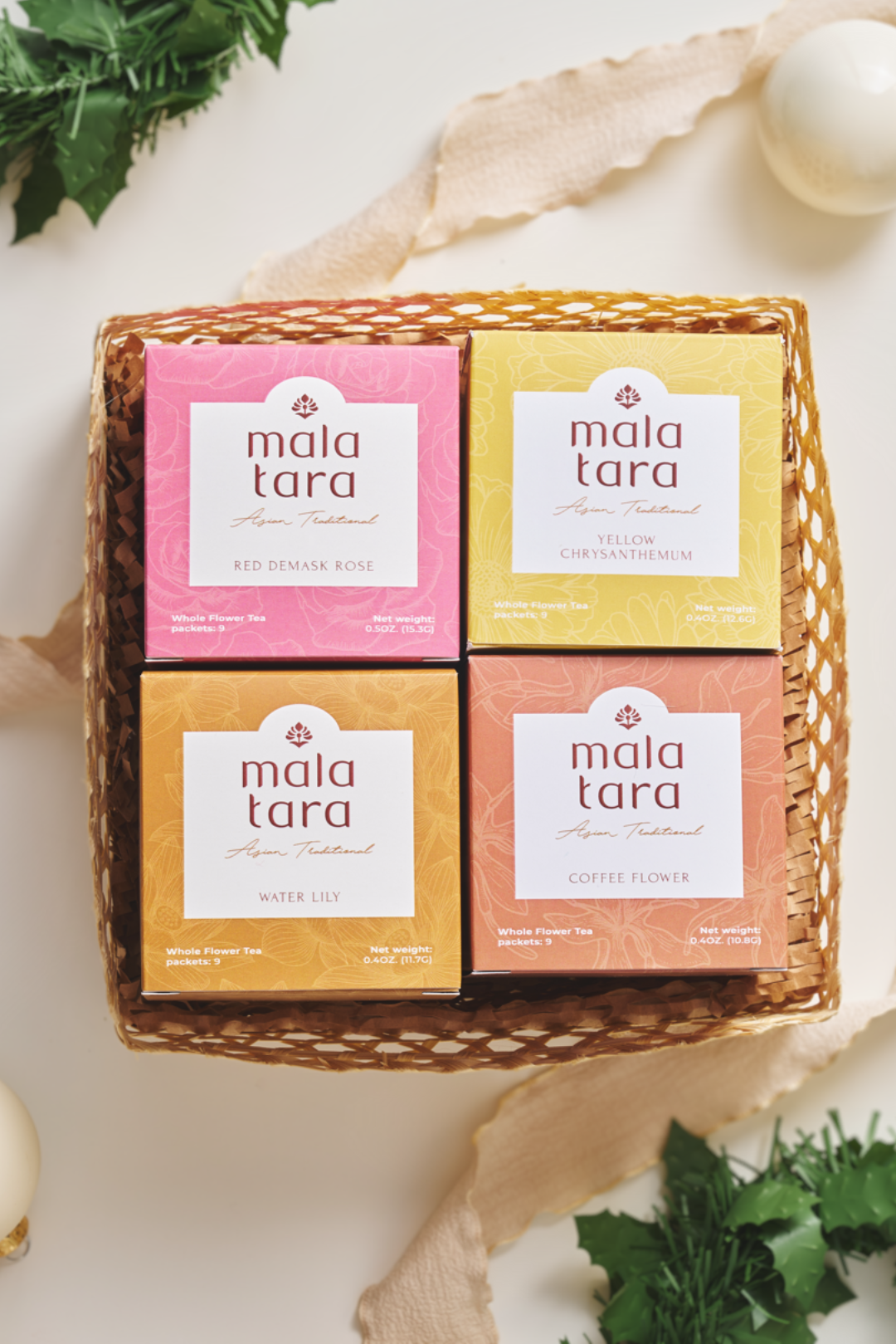 Four boxes of Mala Tara tea in a woven basket on a light background with decorative elements.