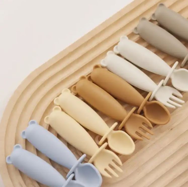 Set of colorful plastic cutlery on a wooden tray