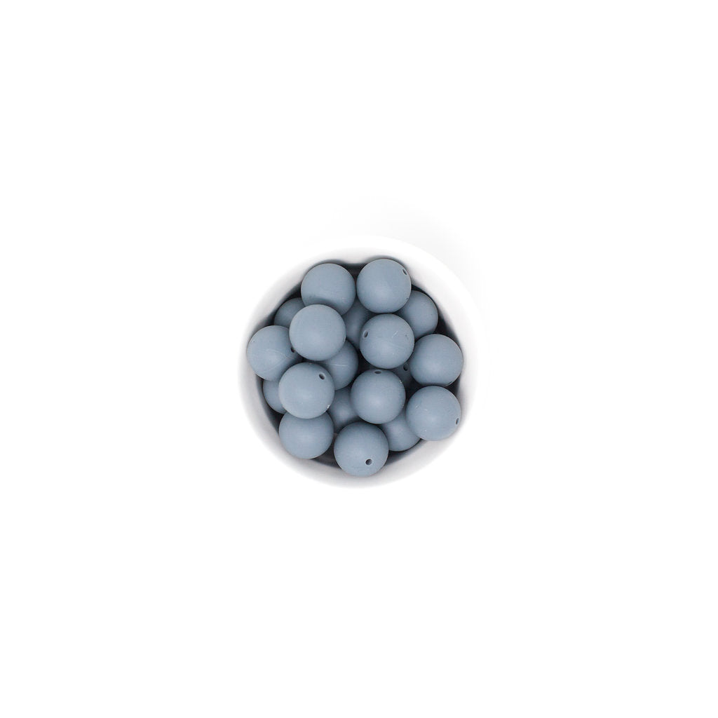 Gray beads in a small round container on a white background