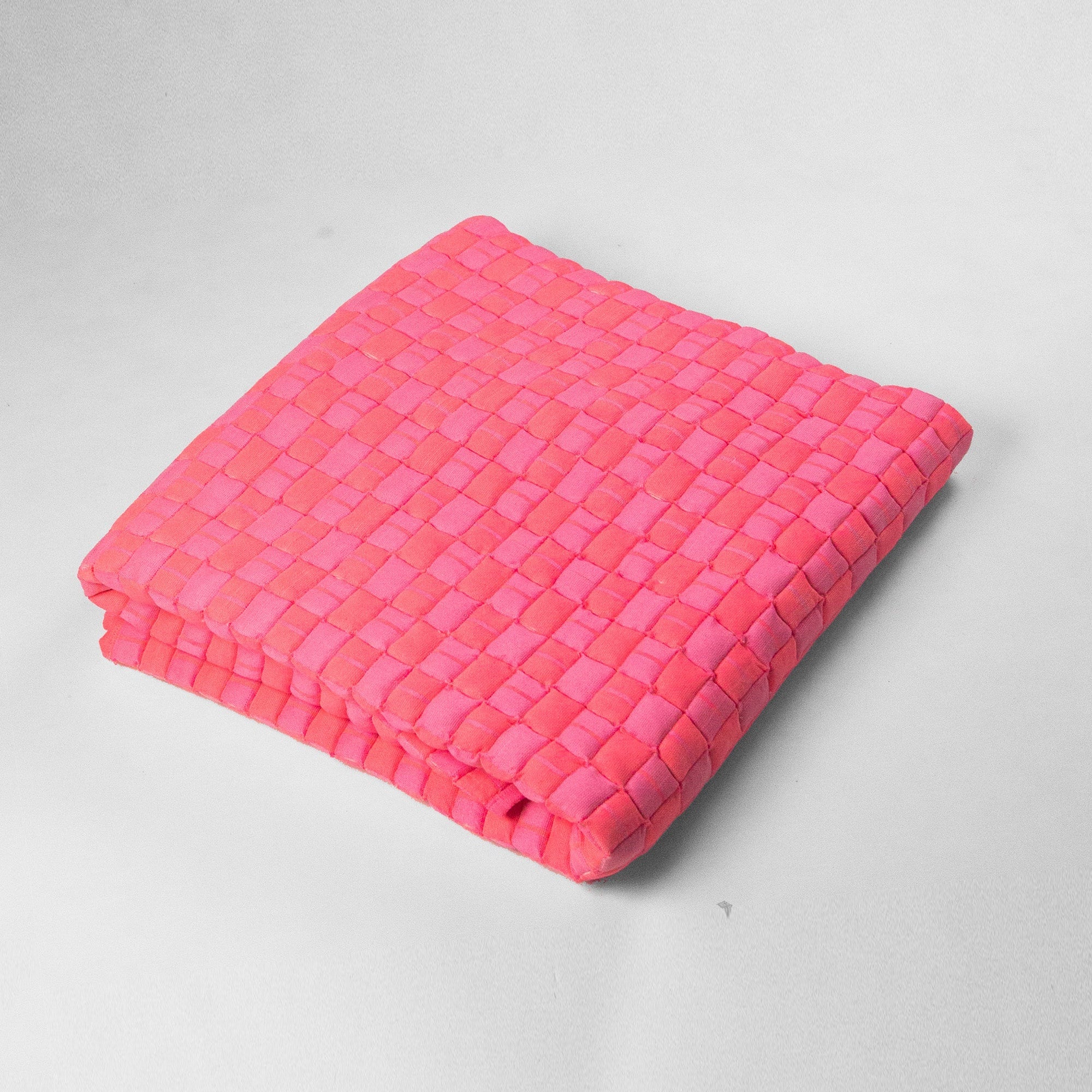 Pink woven blanket on a light gray background