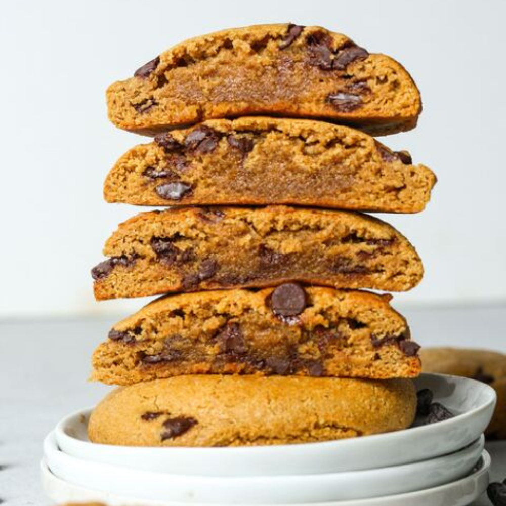 Stack of chocolate chip cookies with a gooey chocolate filling on a white plate.