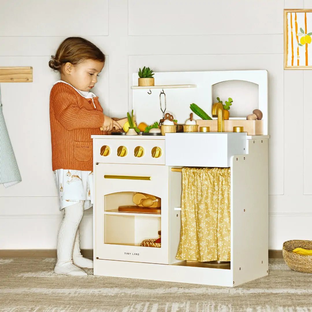 Child playing with a toy kitchen set in a bright room