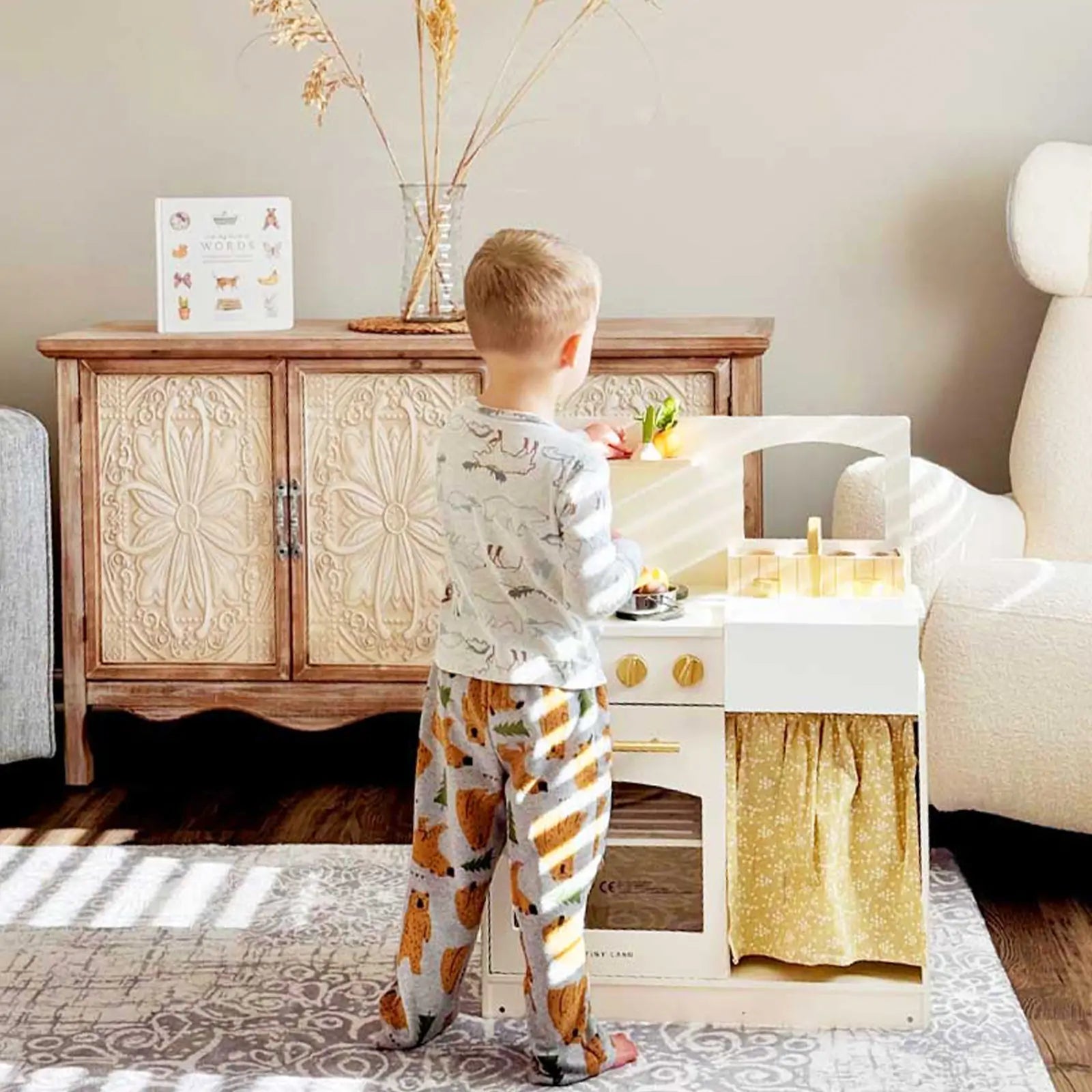 Child playing with a toy kitchen set in a living room.