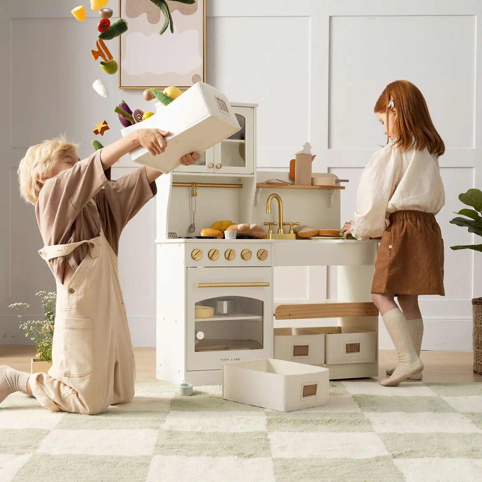 Two children playing with a toy kitchen set in a bright room.