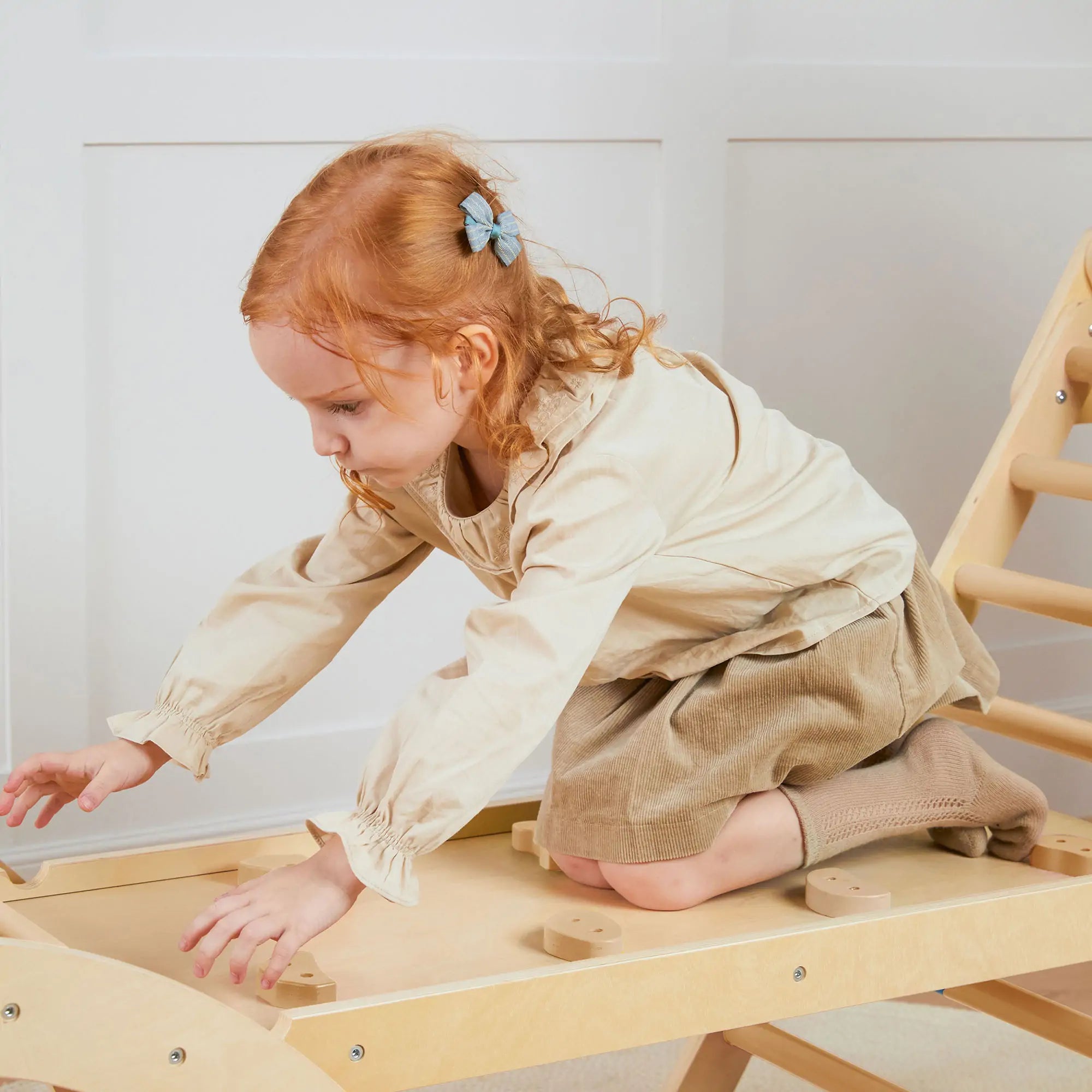 Child playing with a wooden toy on a light-colored floor.