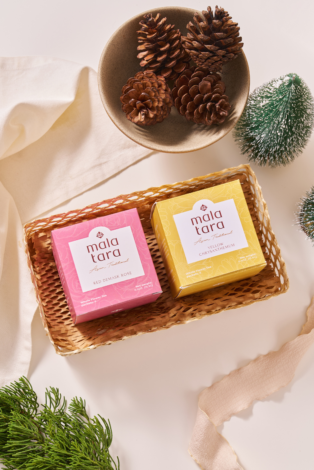 Two soap bars from Mala Tara in a woven basket with decorative elements on a light background