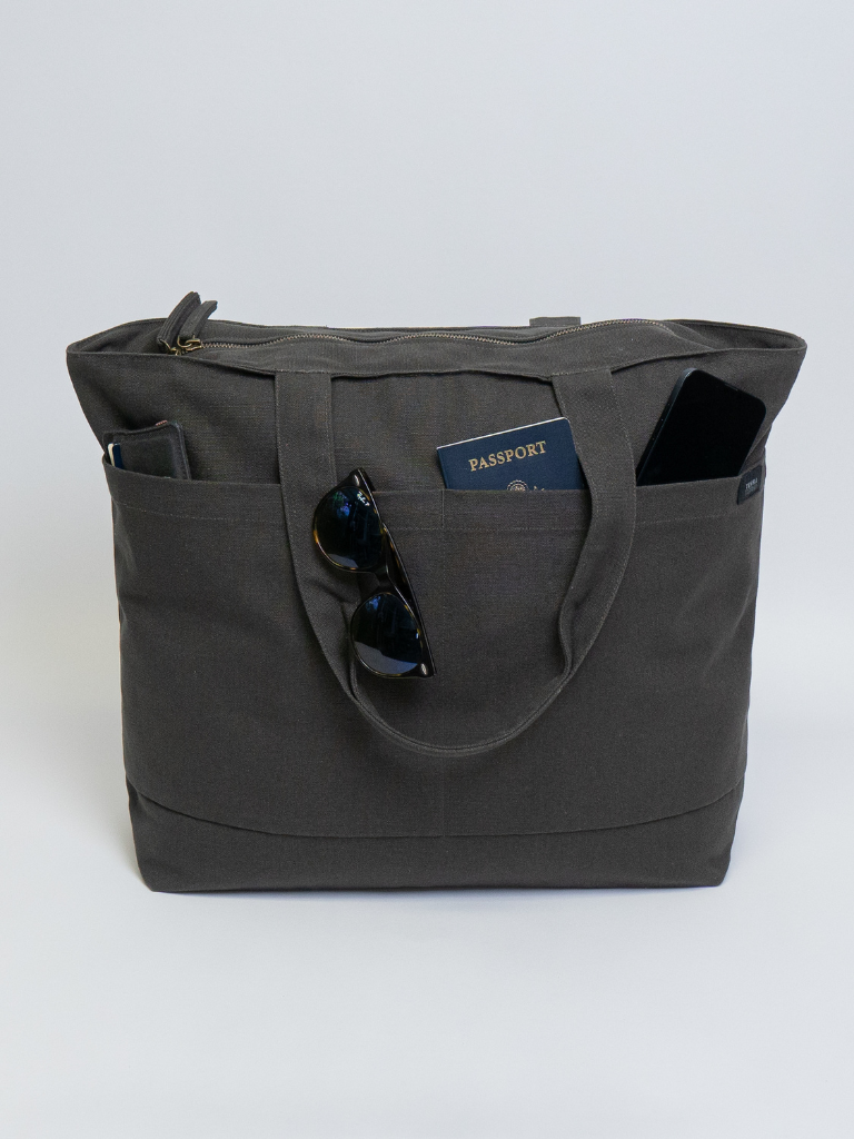 Gray tote bag with sunglasses and a passport on a white background