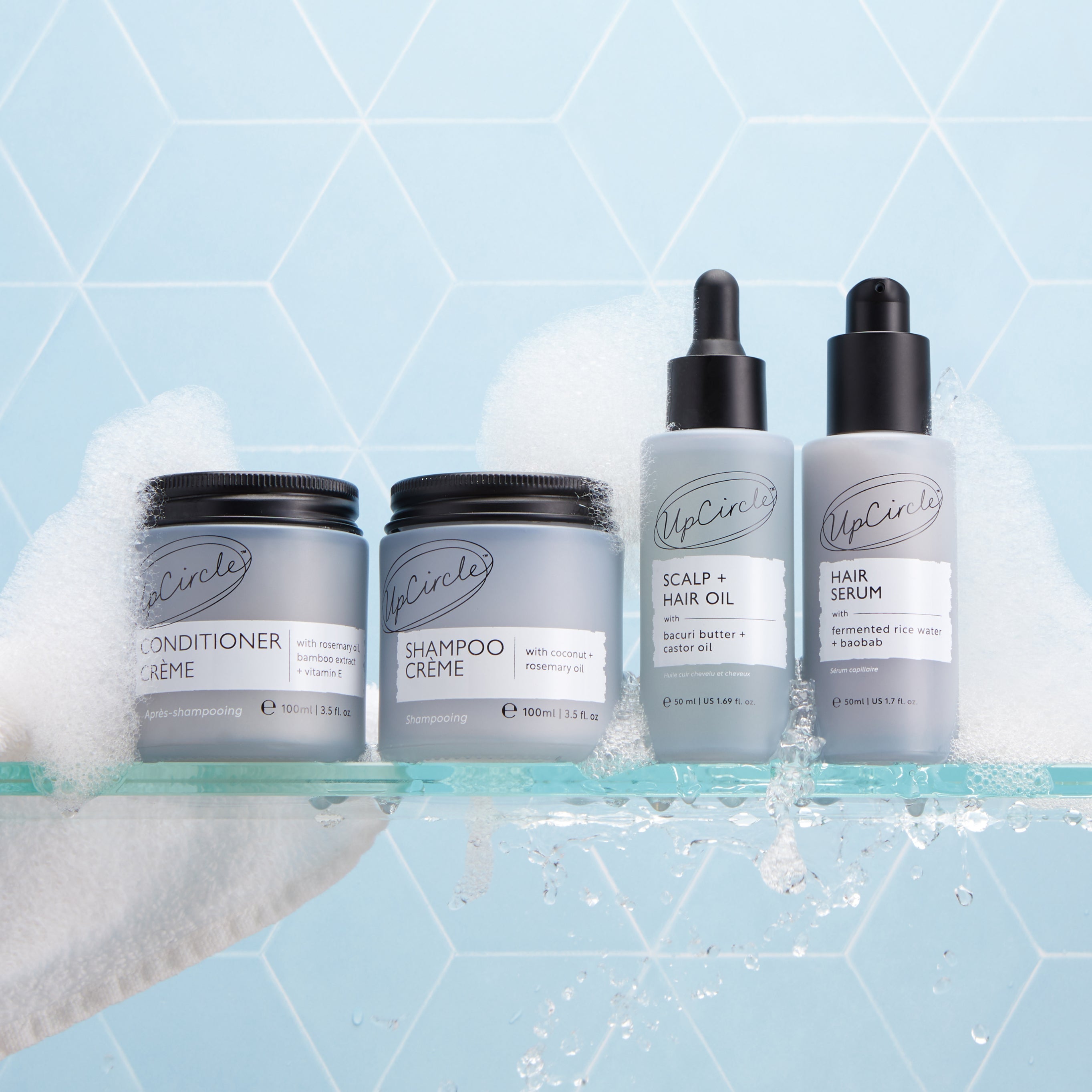 Set of hair care products including conditioner, shampoo, oil, and serum with a blue geometric background.