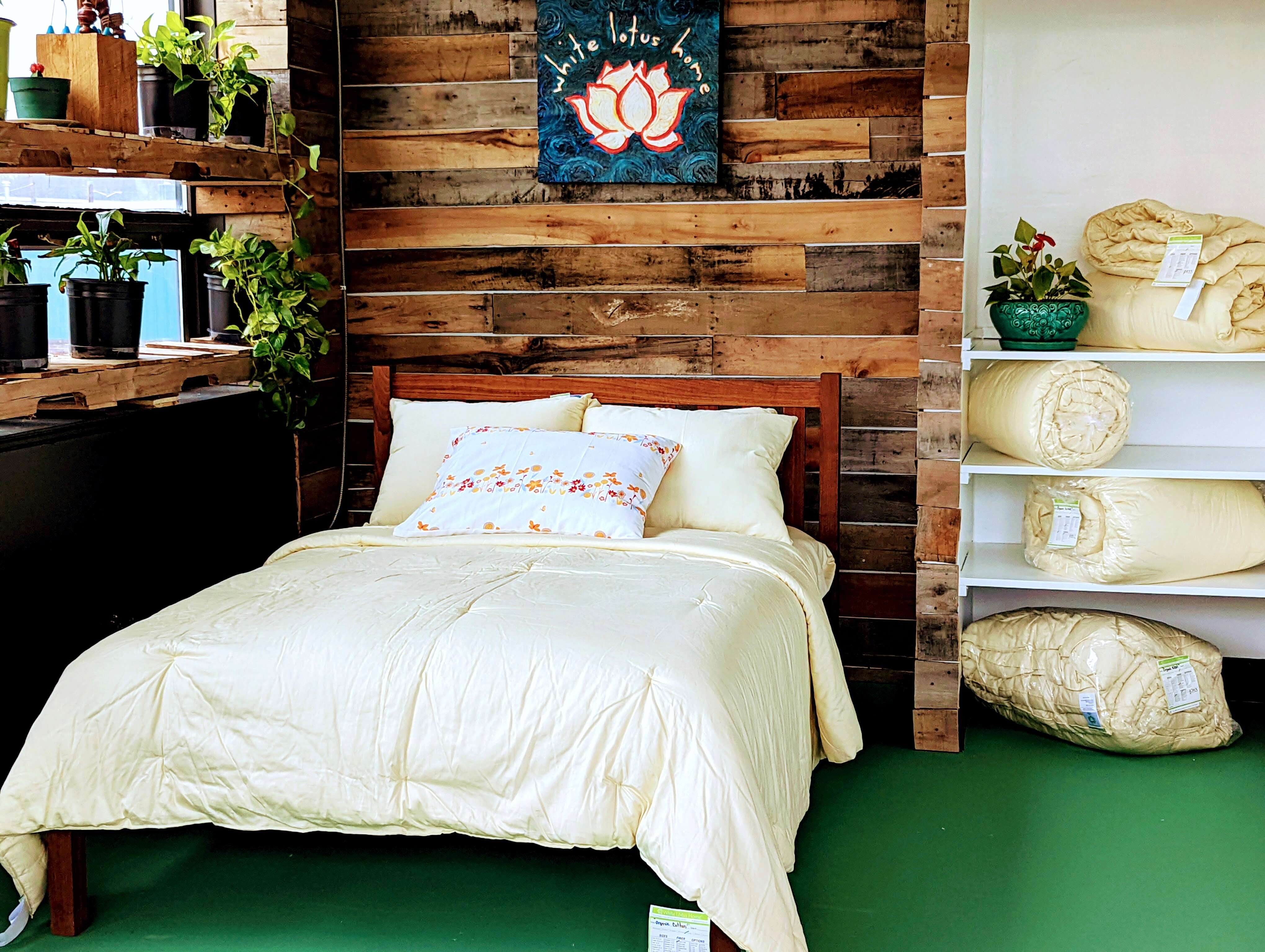 Bedroom with wooden headboard, white bedding, and decorative pillows against a wooden wall.