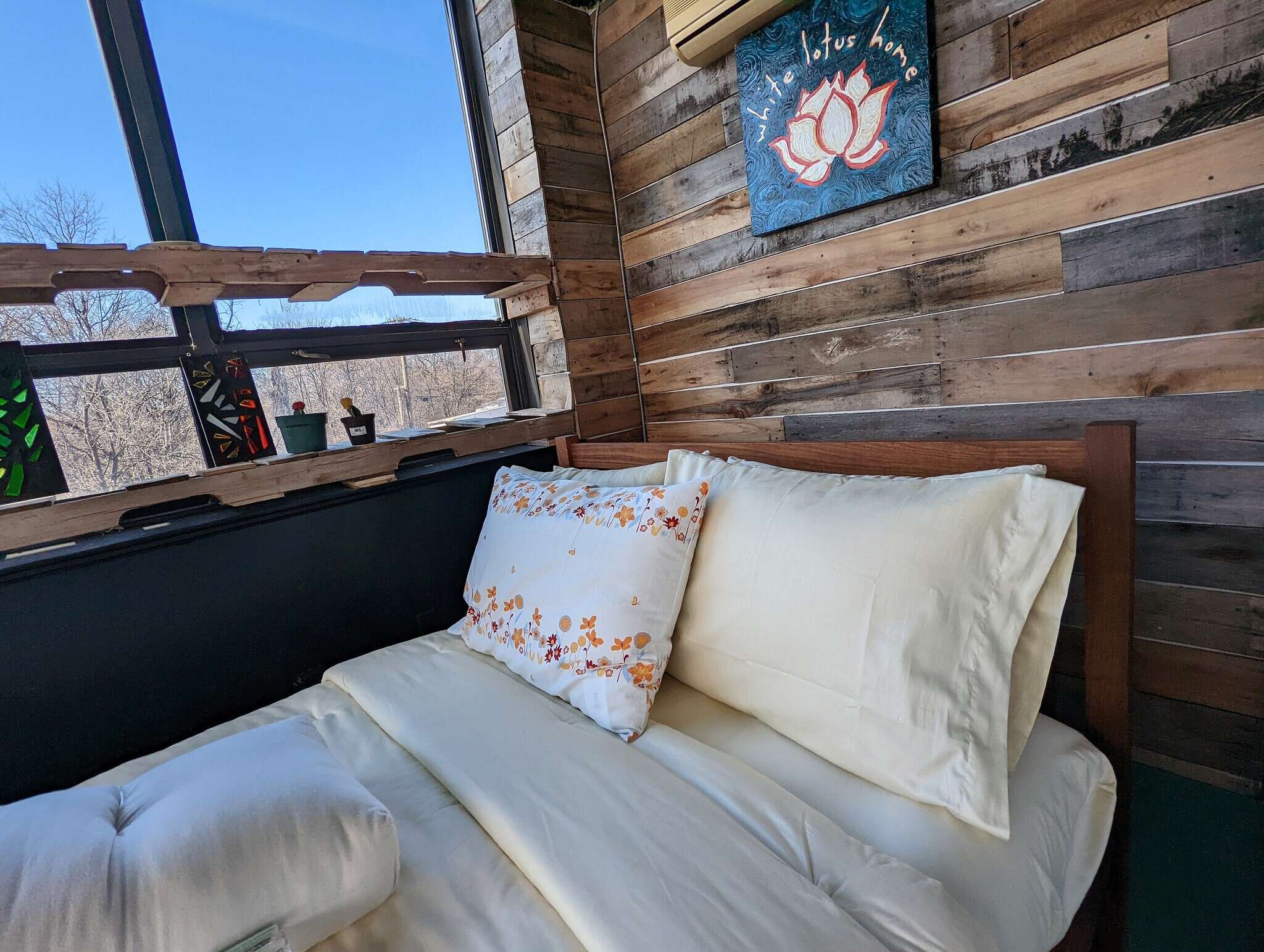 Bedroom with wooden walls, a bed with pillows, and a window view.