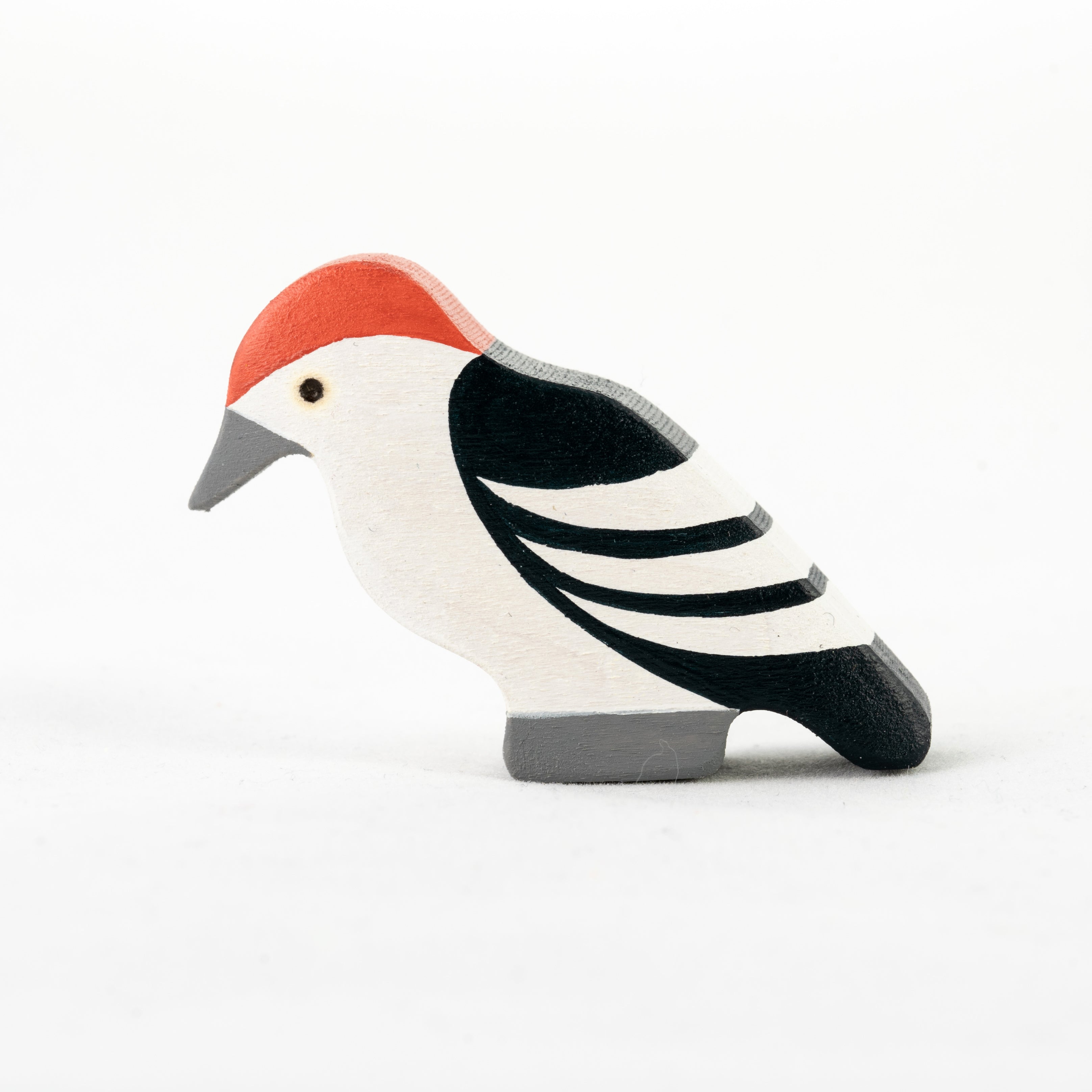 Wooden bird figurine with a red cap on a white background