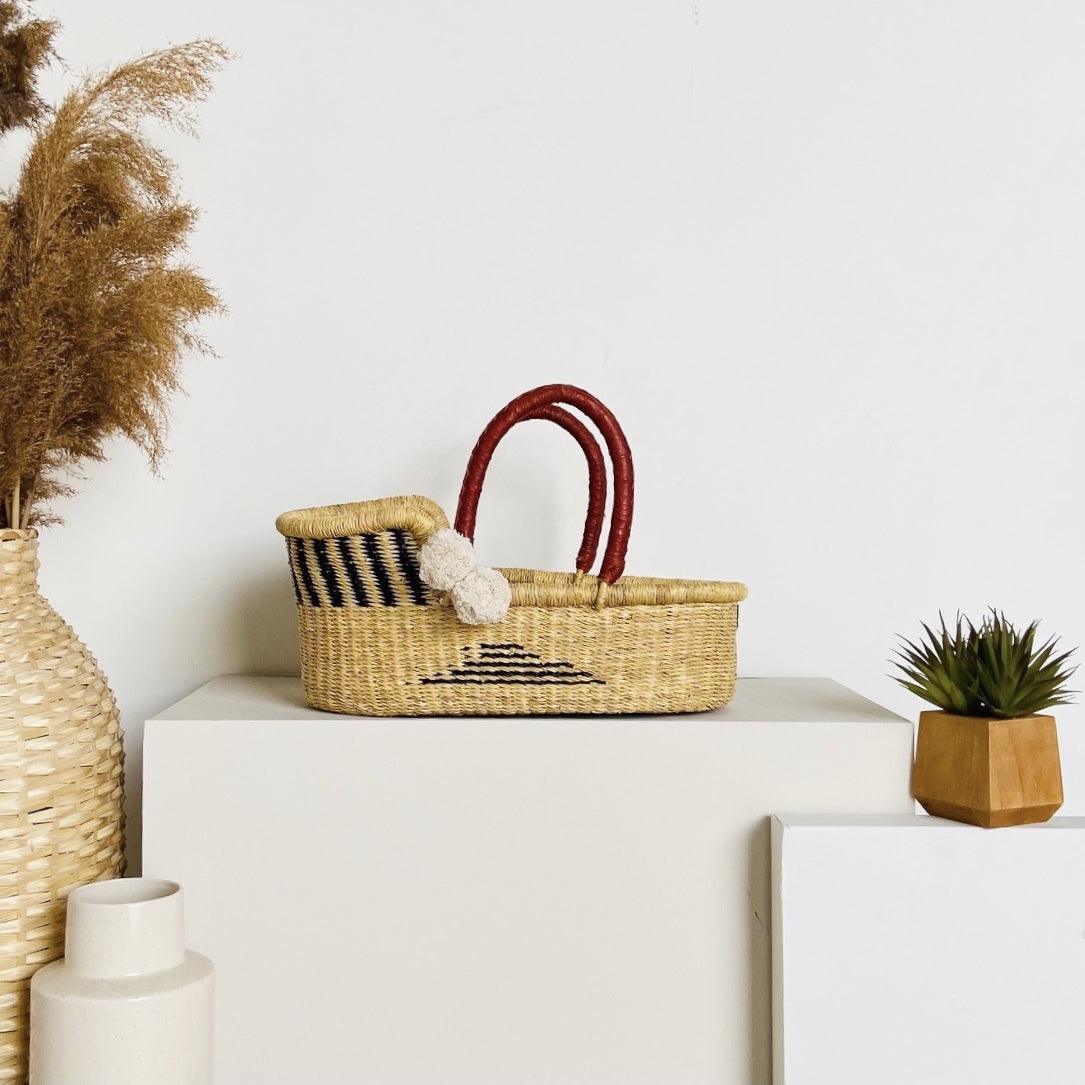 Woven basket with striped pattern on a white surface, surrounded by decorative items.