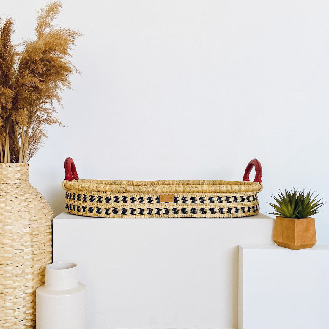 Woven baskets with handles on a white surface, surrounded by decorative items.