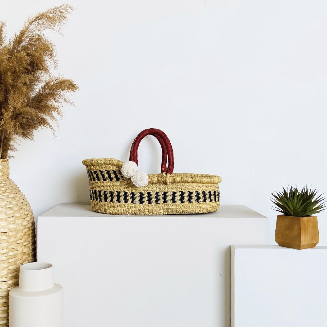 Woven basket with striped pattern on a white surface, surrounded by decorative items.