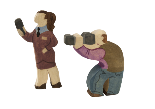 Wooden figurines of a woman taking a photo and a man taking a photograph on a white background