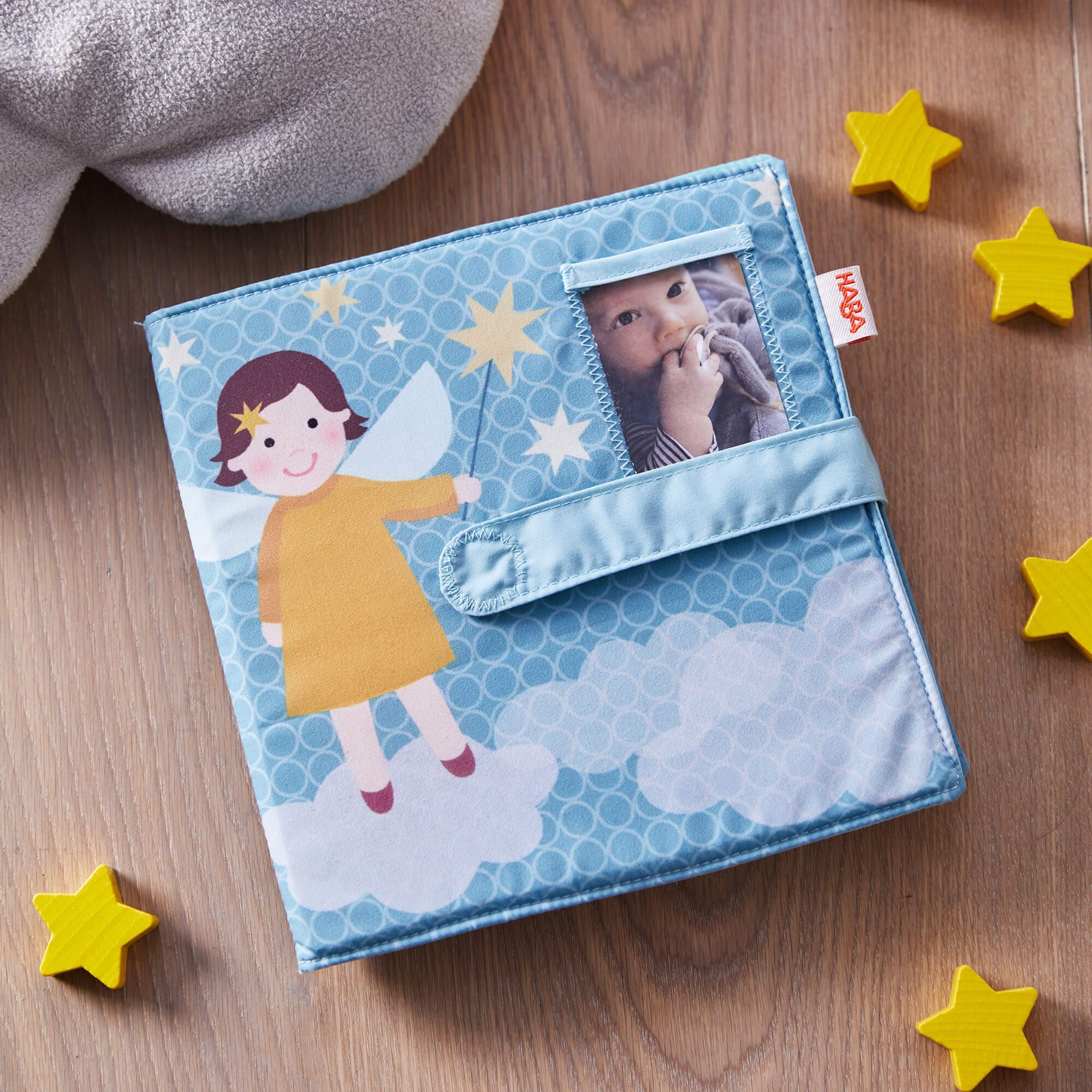 Children's photo album with a fairy design on a wooden surface with star-shaped objects.