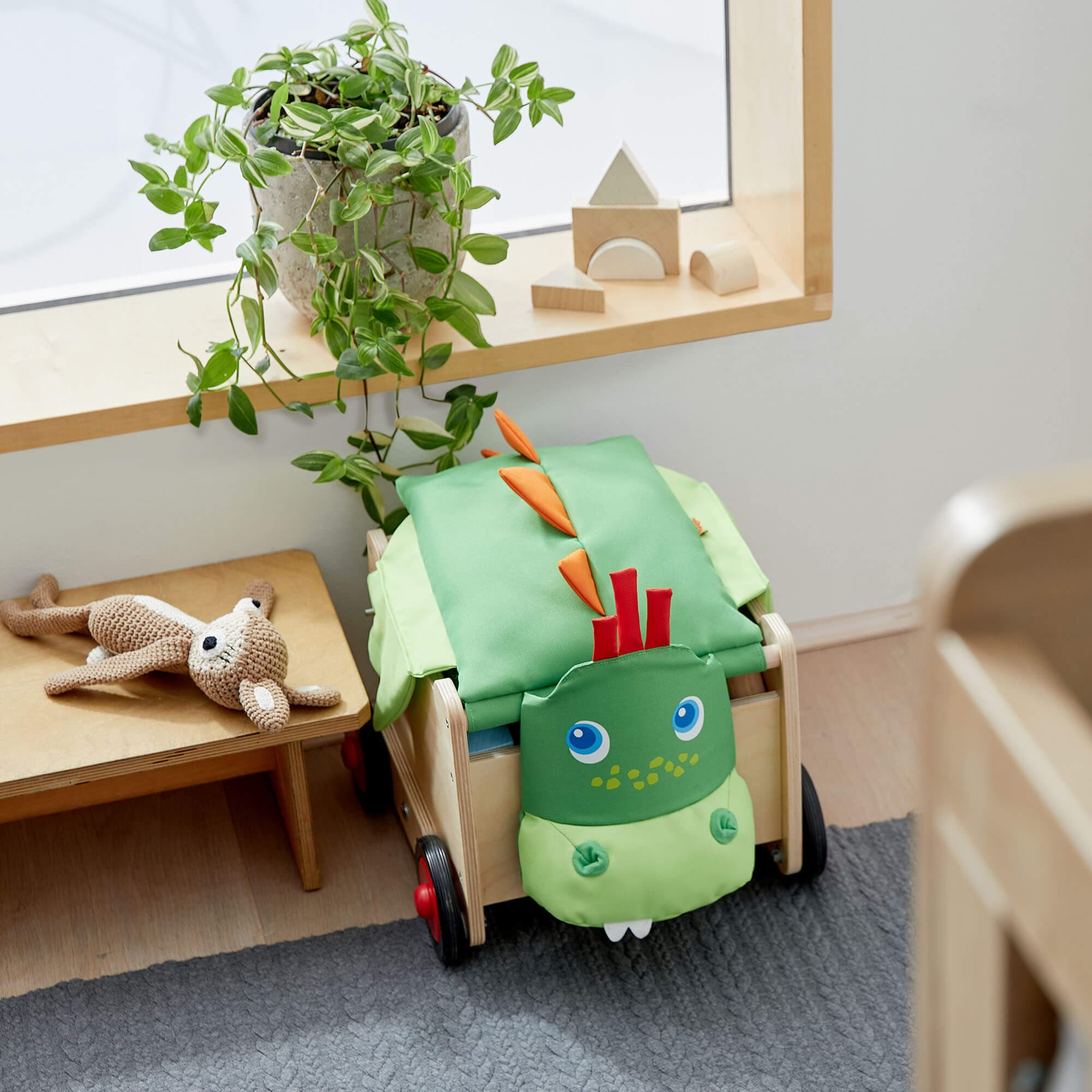 Children's room with a green dinosaur-shaped chair, plant, and toys.