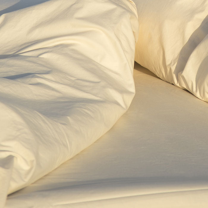 Close-up of a white comforter and pillows on a bed