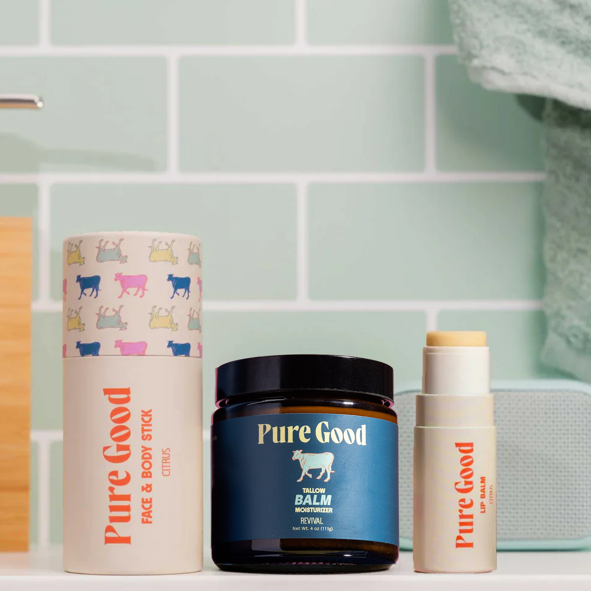 Collection of Pure Good skincare products on a bathroom shelf with a tiled wall background.