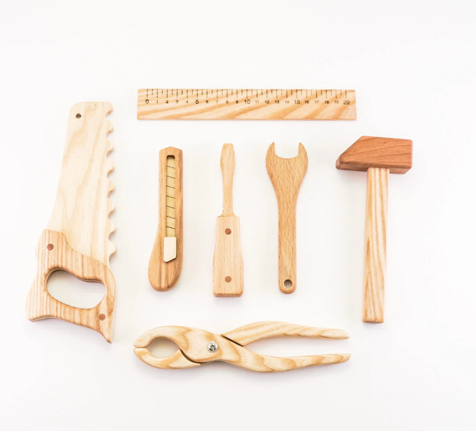 Set of wooden tools including a saw, pliers, and other implements on a white background