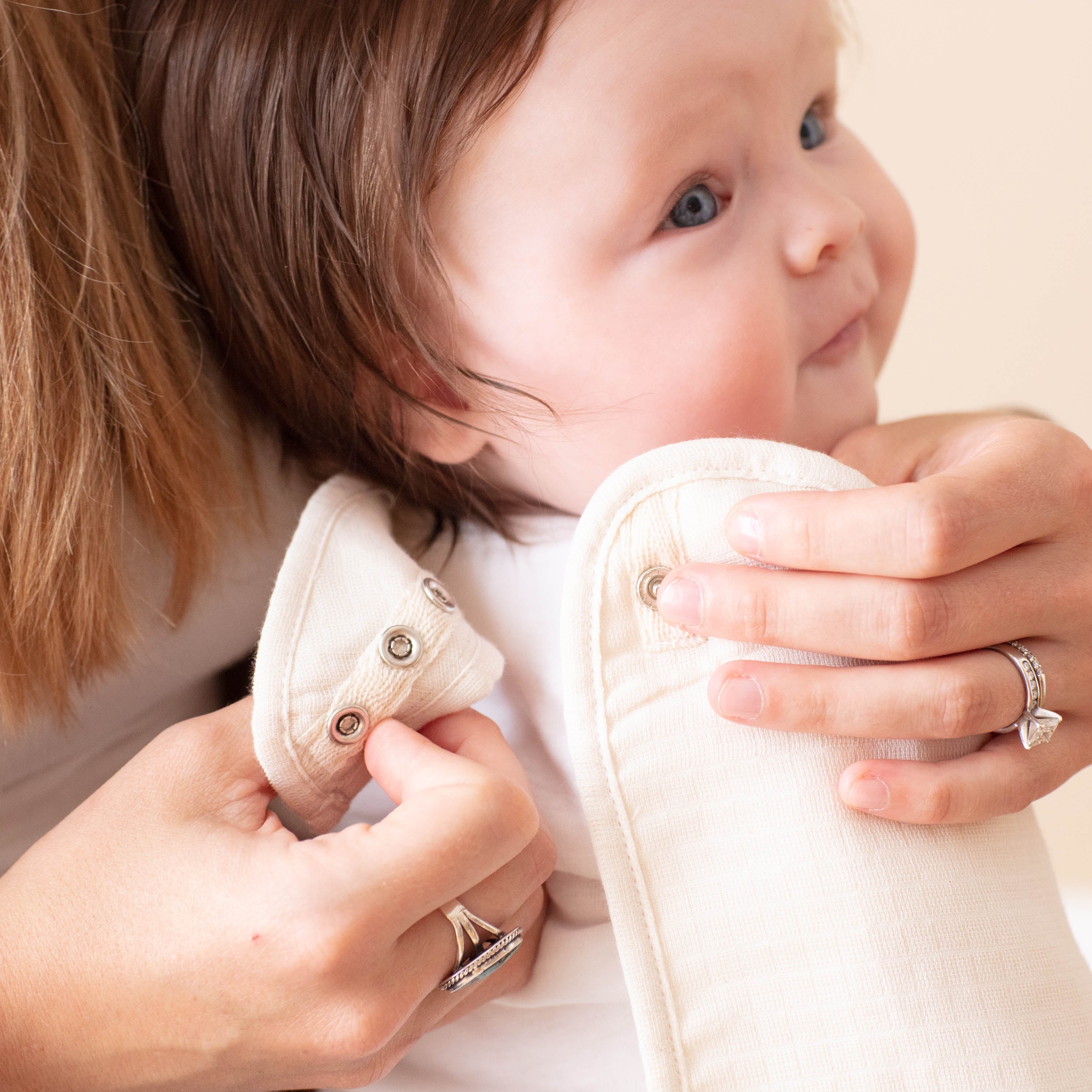 Baby being held by a person wearing white shoes with visible buttons.