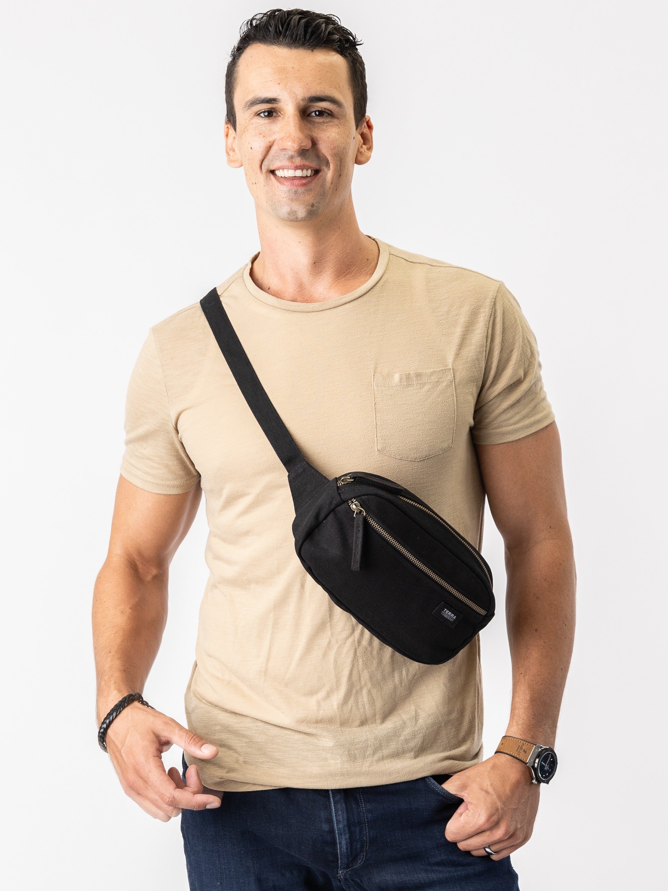 Man wearing a beige t-shirt with a black crossbody bag on a white background