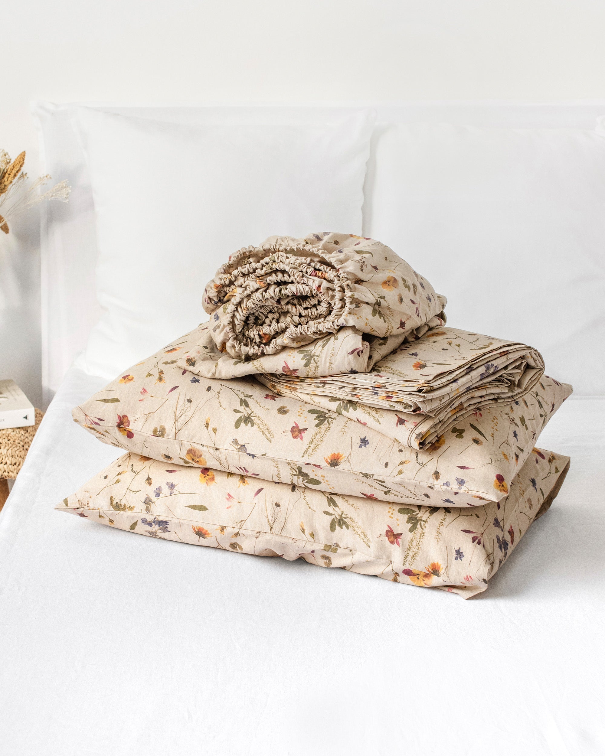 Folded floral-patterned bedding set on a white bed