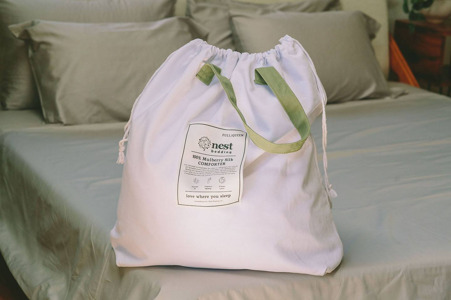 White drawstring bag with a label on a bed