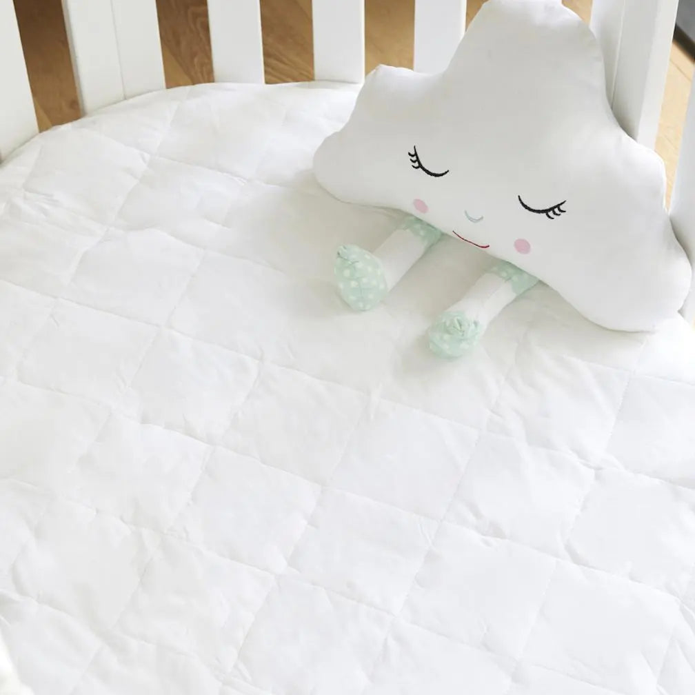 White cloud-shaped pillow with cartoon face on a crib
