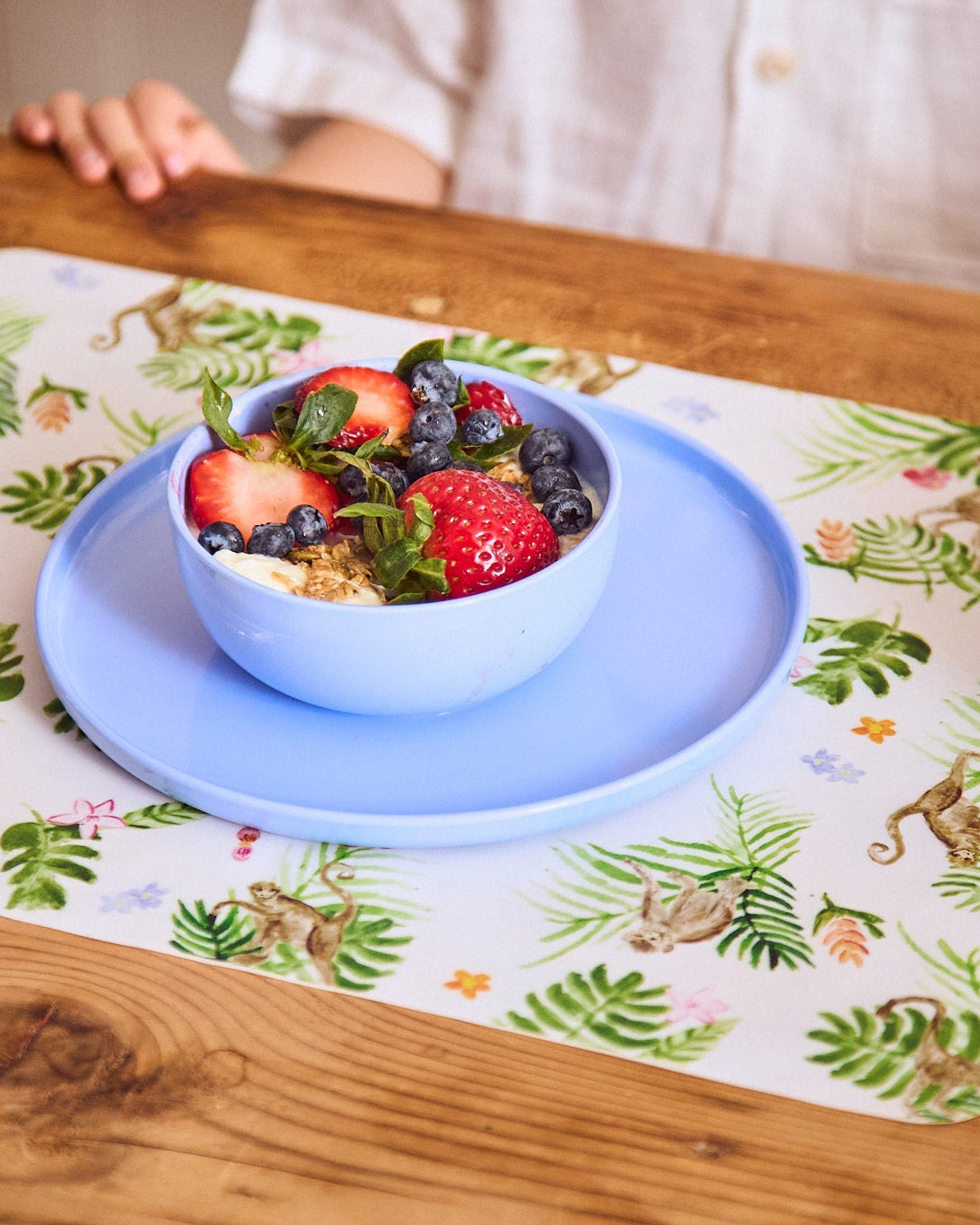 Bowl of berries on a blue plate with a colorful tablecloth underneath