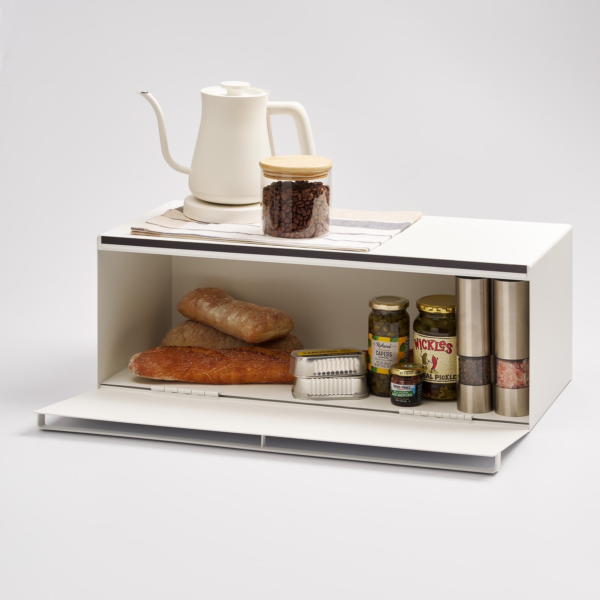 White kitchen shelf with bread, jars, and a kettle on a light gray background