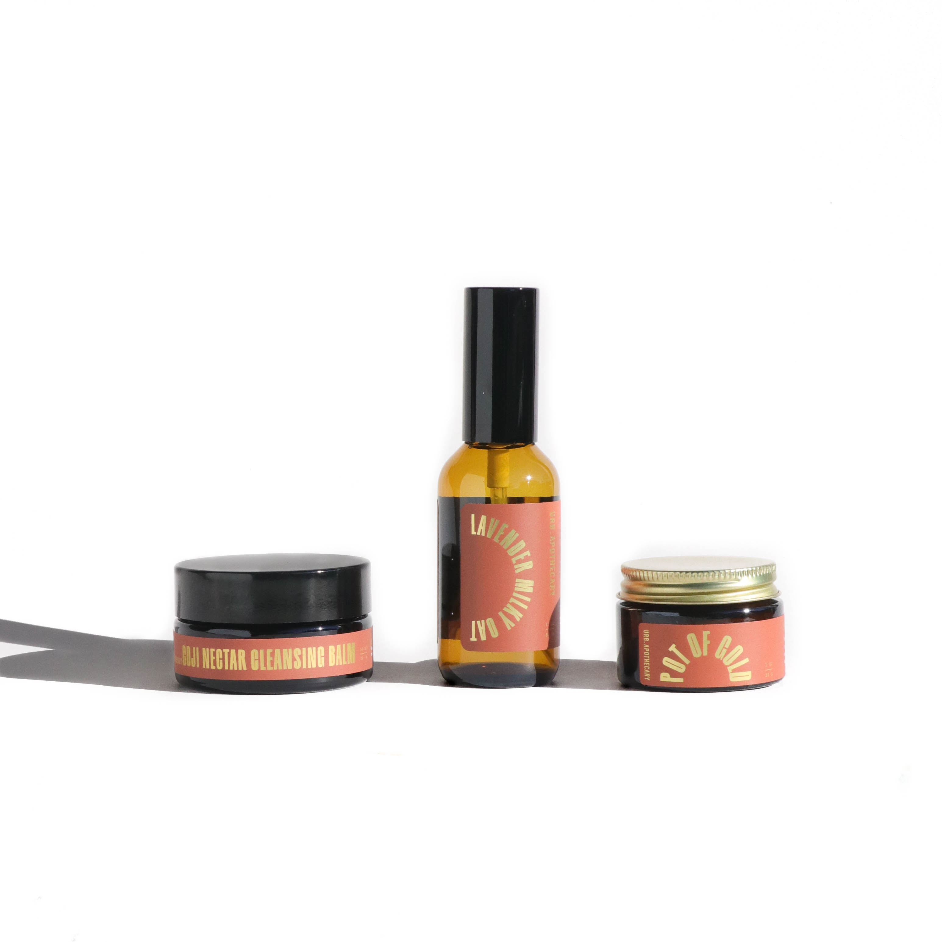 Three cosmetic products with pink labels and black lids on a white background