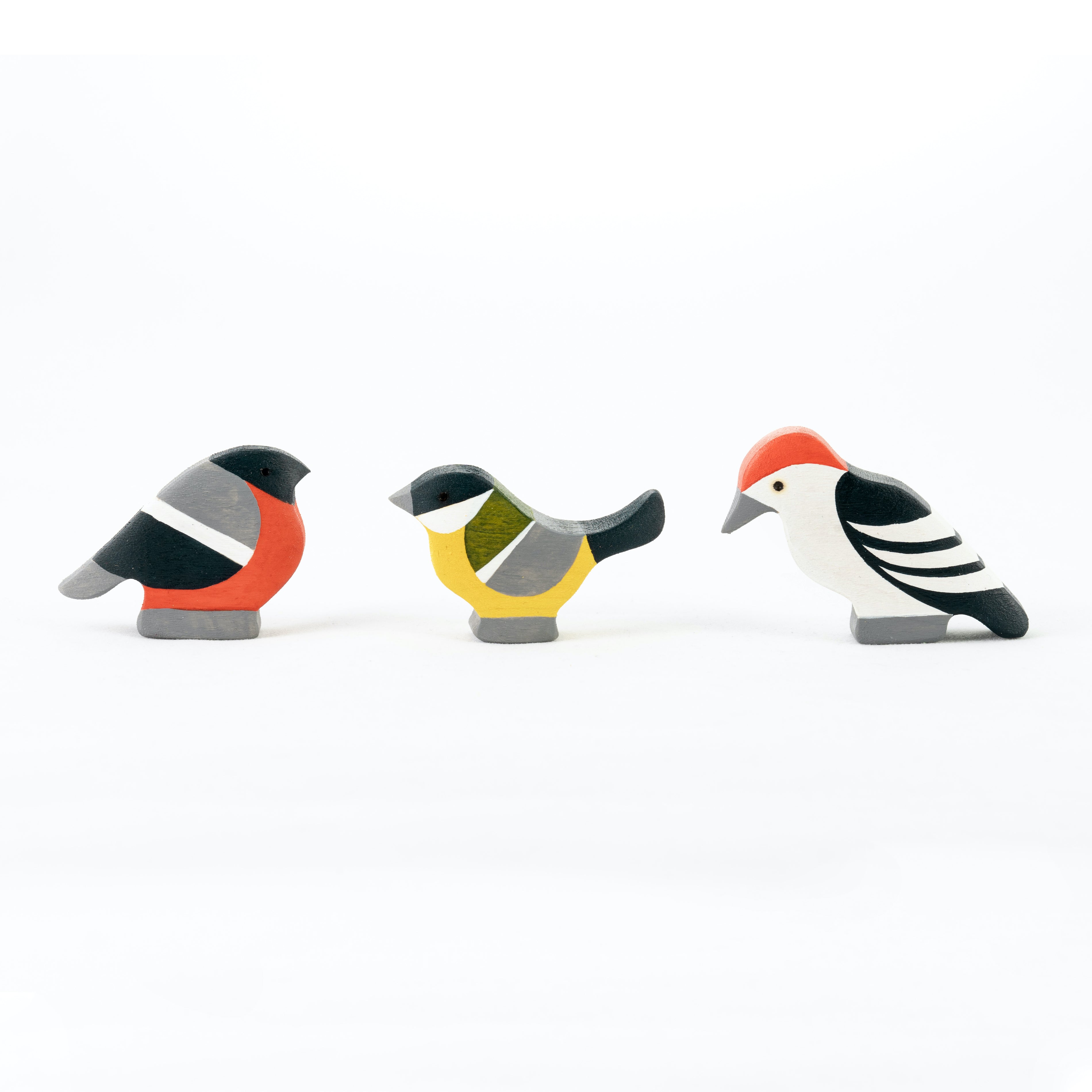 Three wooden bird figurines on a white background
