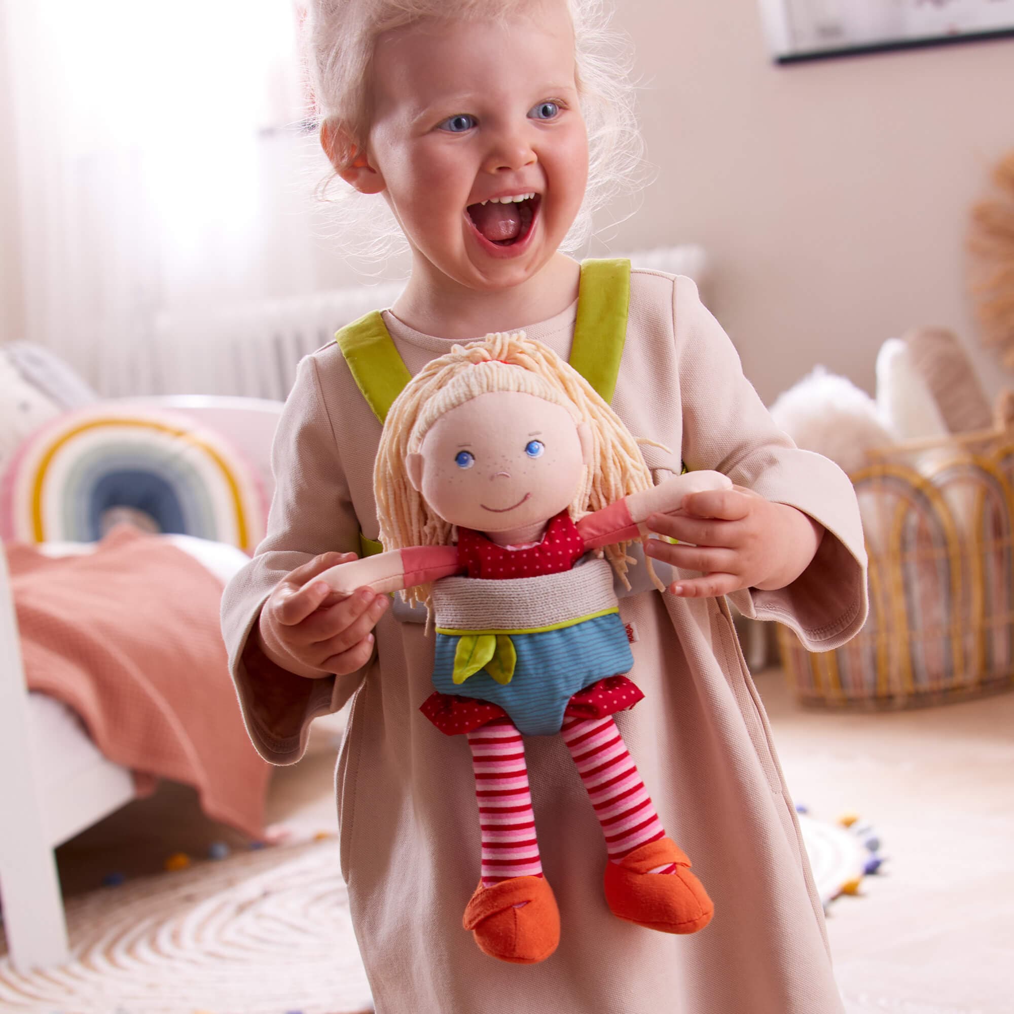 Child holding a doll in a room with toys and furniture
